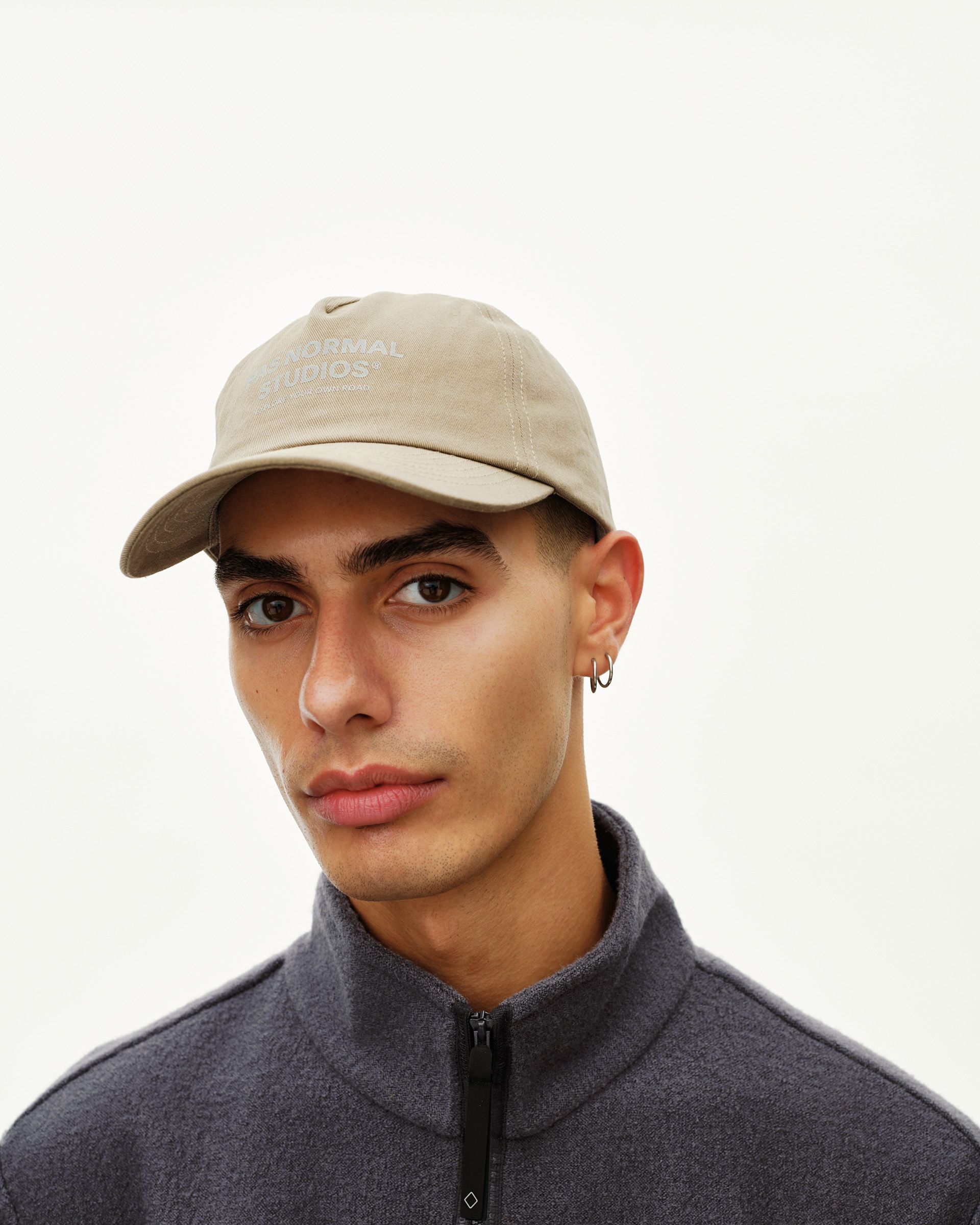 Dusty Earth khaki Off-Race Cotton cap on model, front view with tonal logo print on crown