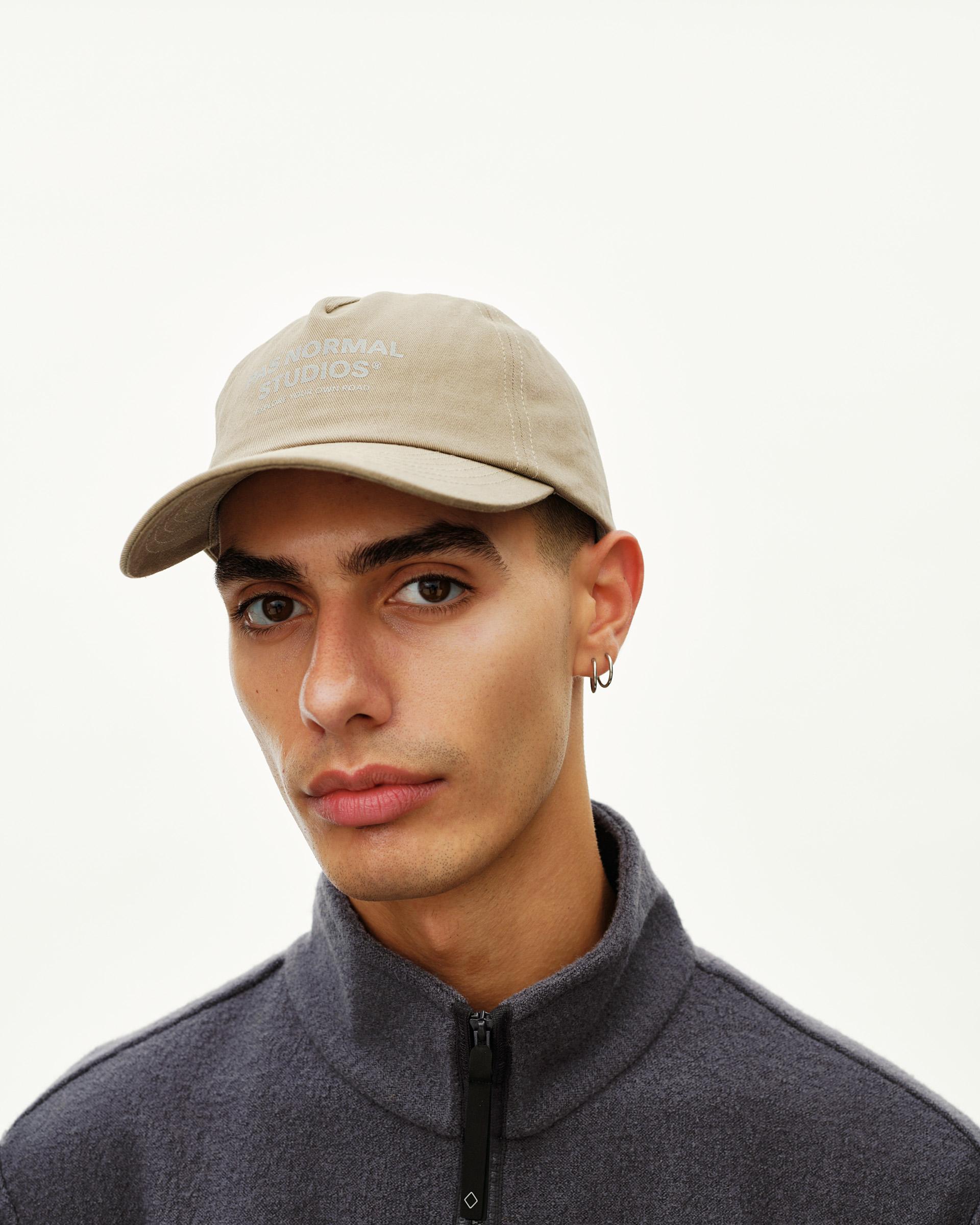 Dusty Earth khaki Off-Race Cotton cap on model, front view with tonal logo print on crown