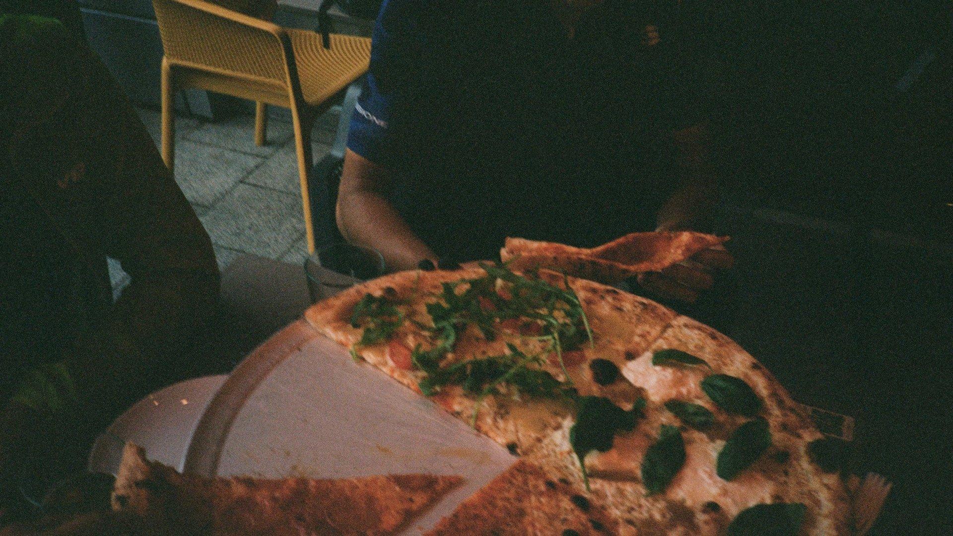 Person eating pizza in dimly lit restaurant setting