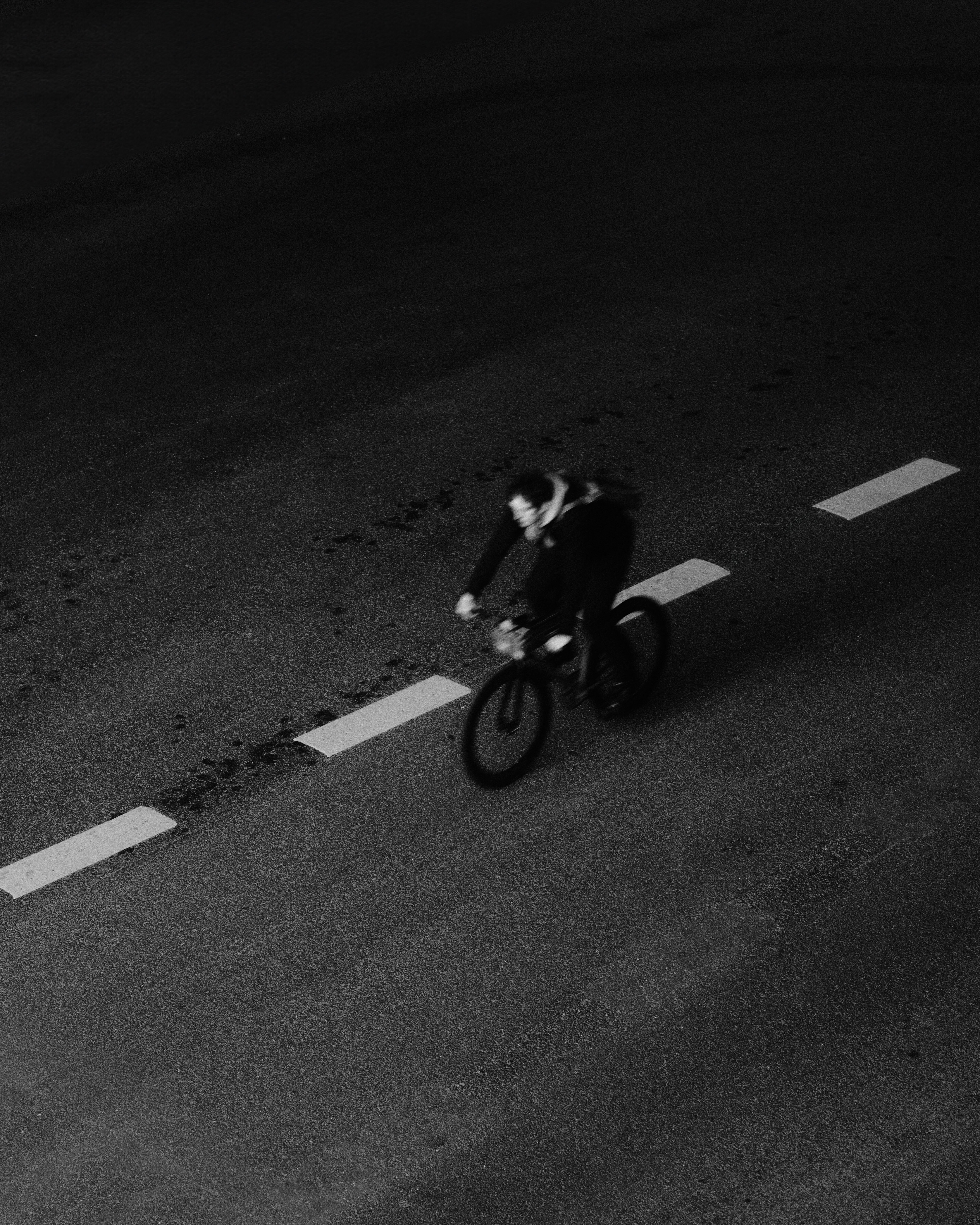 Cyclist riding on road with lane markings in black and white photograph