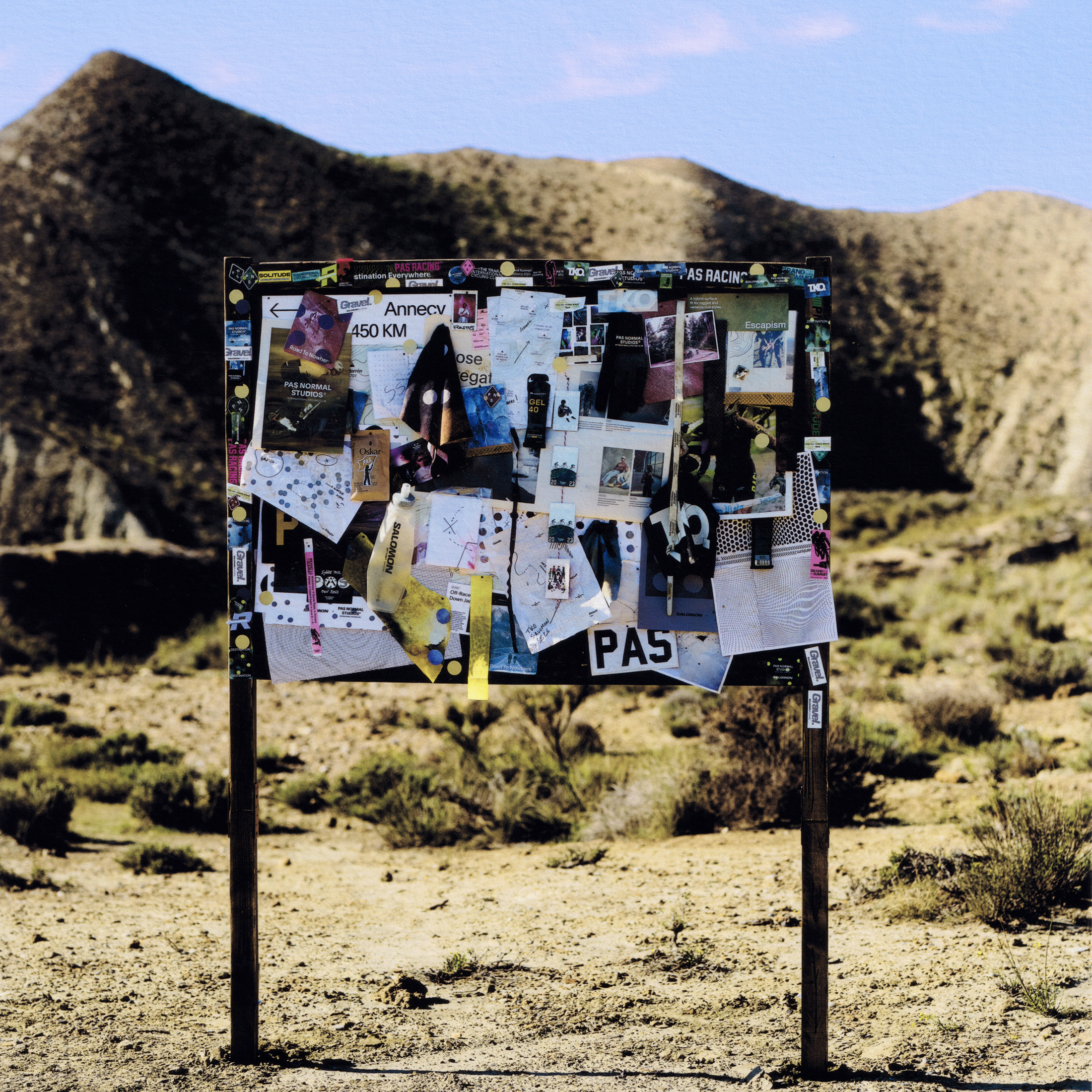 Bulletin board covered in cycling memorabilia and stickers in desert landscape