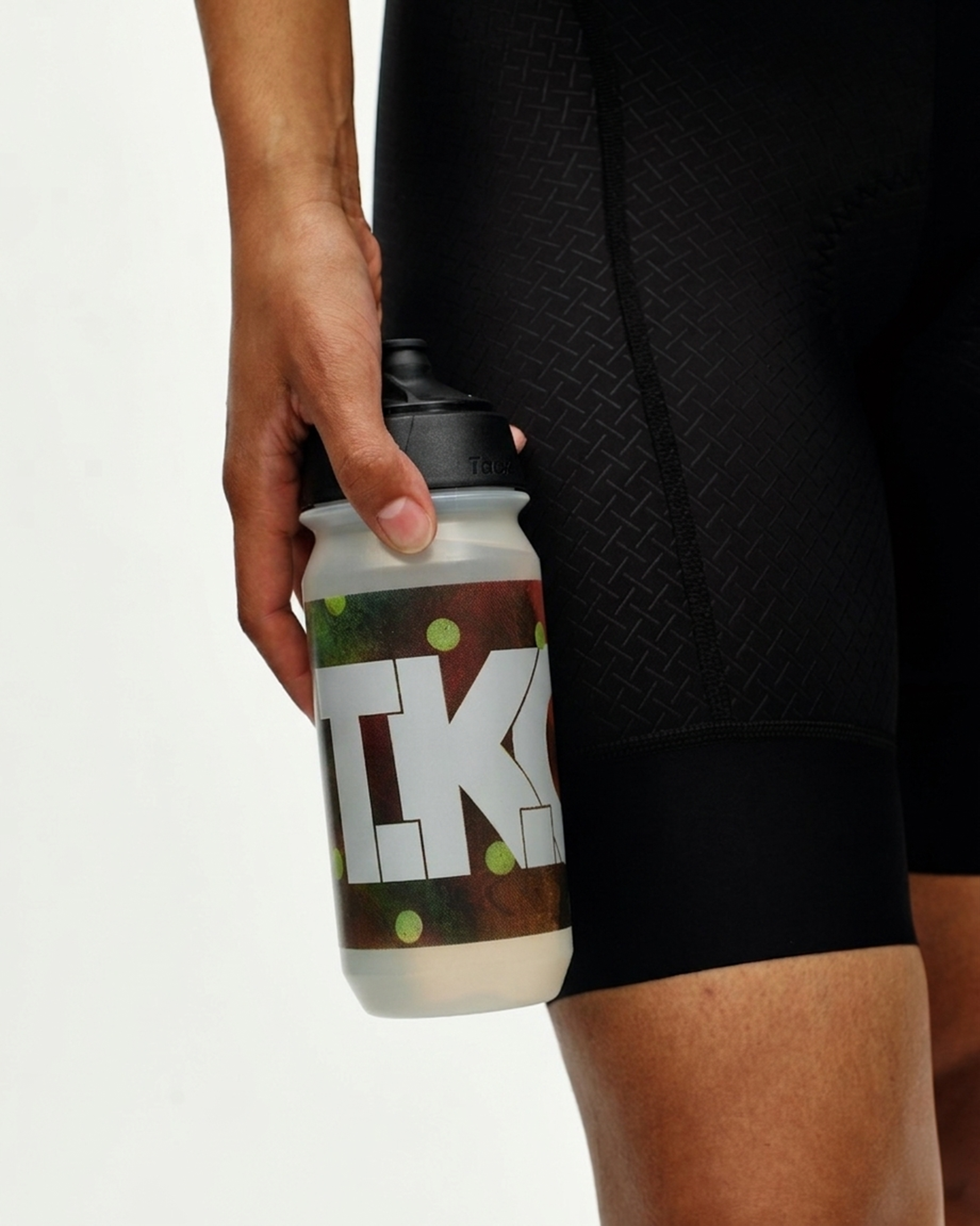 Brown T.K.O. bidon held in hand with camouflage print and white logo