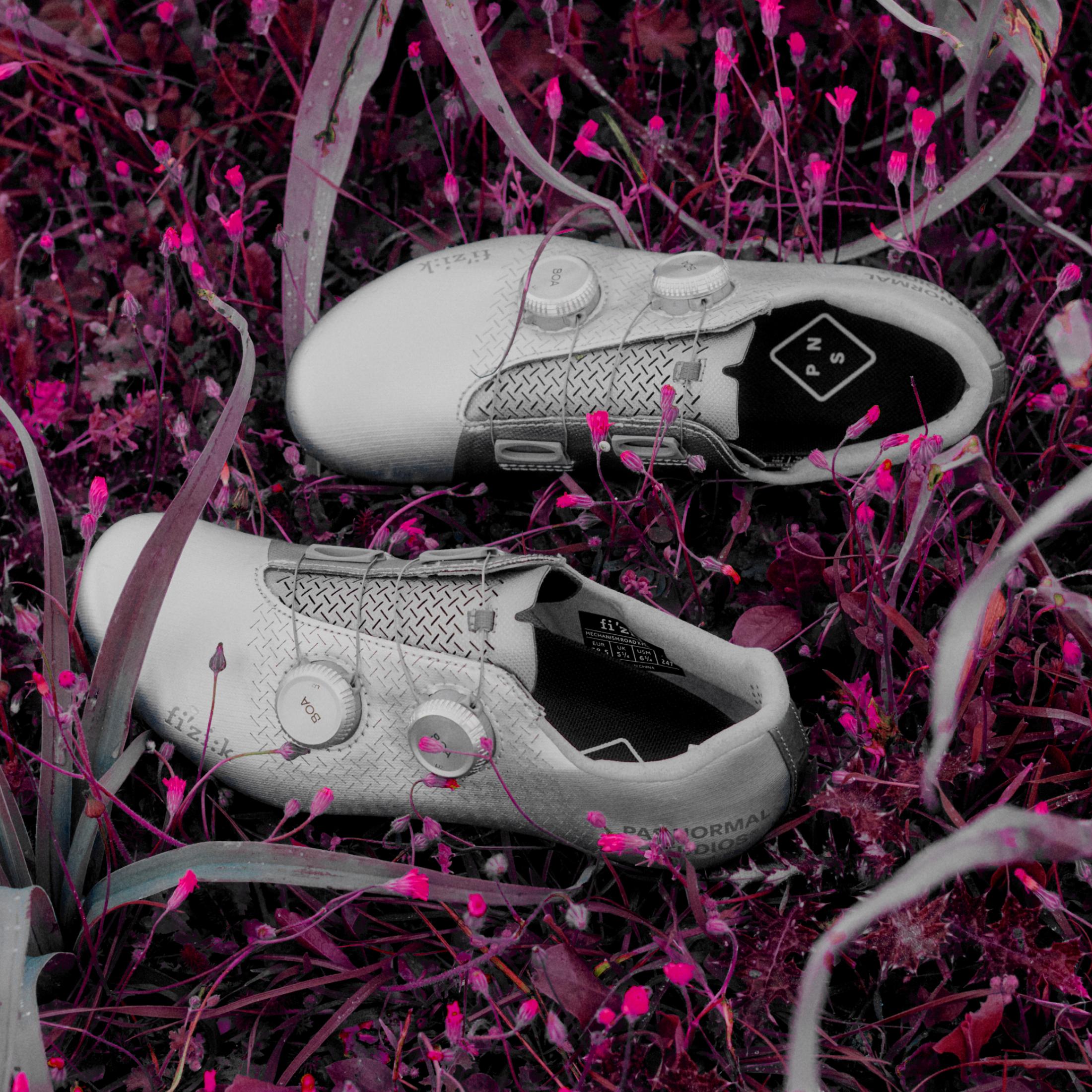 White Fizik cycling shoes with dual BOA dials and textured upper in pink-tinted grass