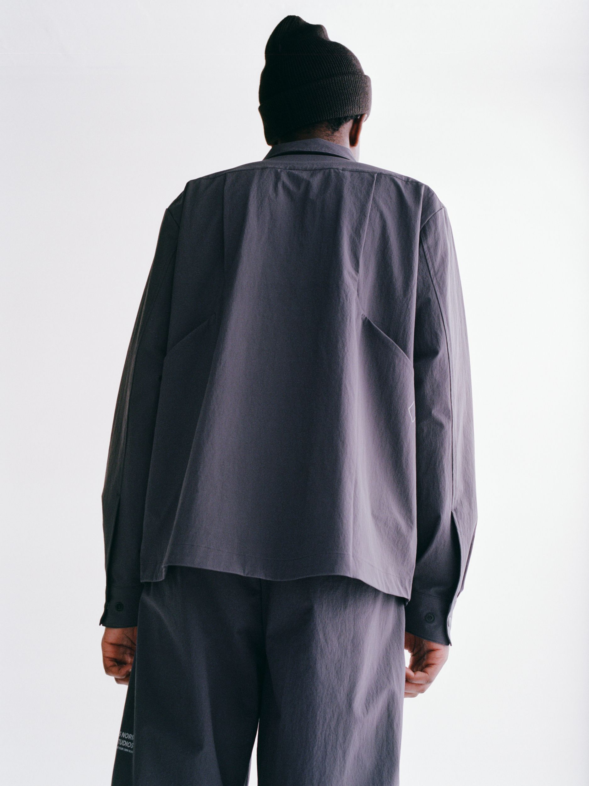 Grey Off-Race Tech pants on model, rear view showing relaxed fit and tapered legs