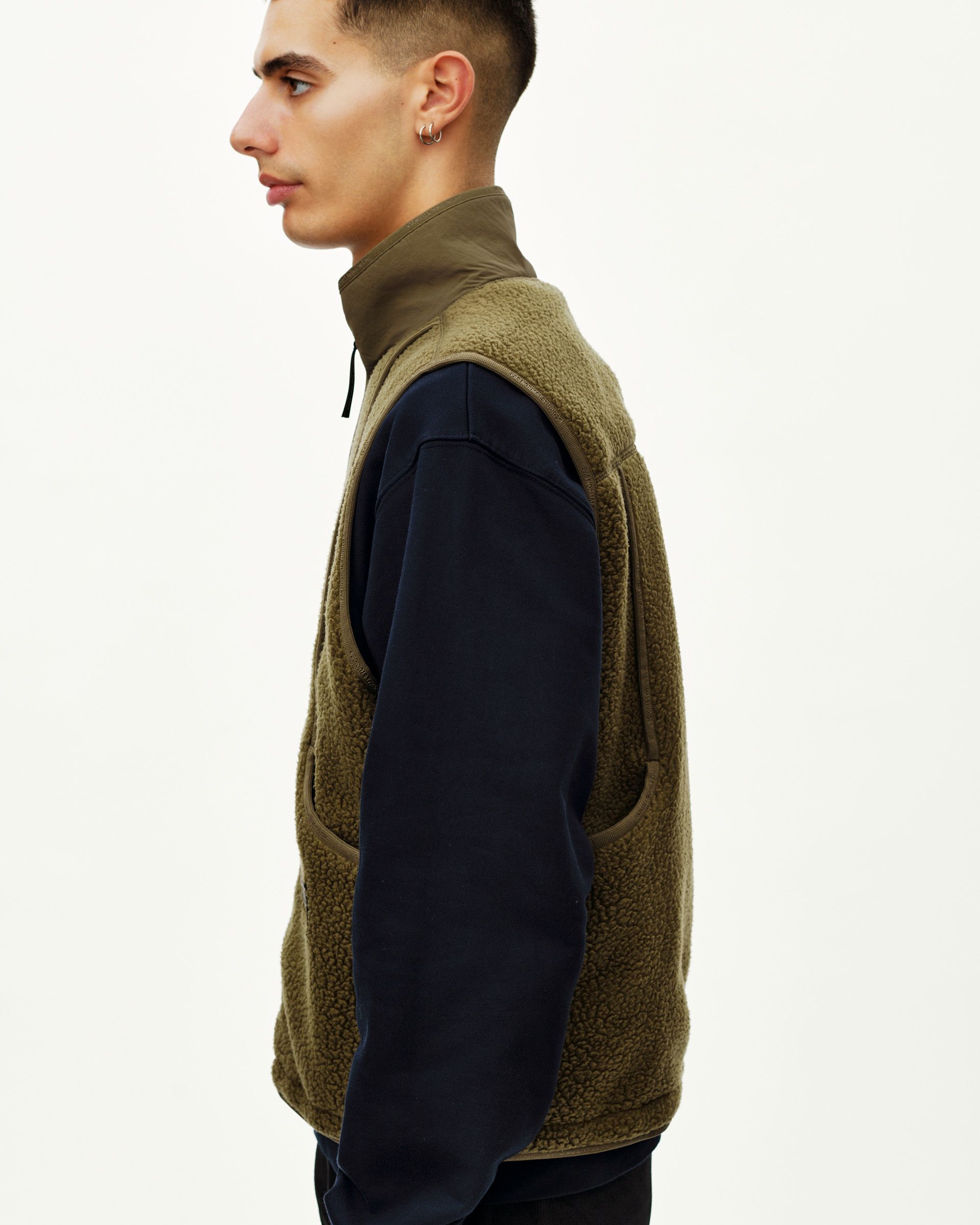 Deep Olive Off-Race Pile Fleece vest on model, side view with sherpa texture and contrast woven collar panel