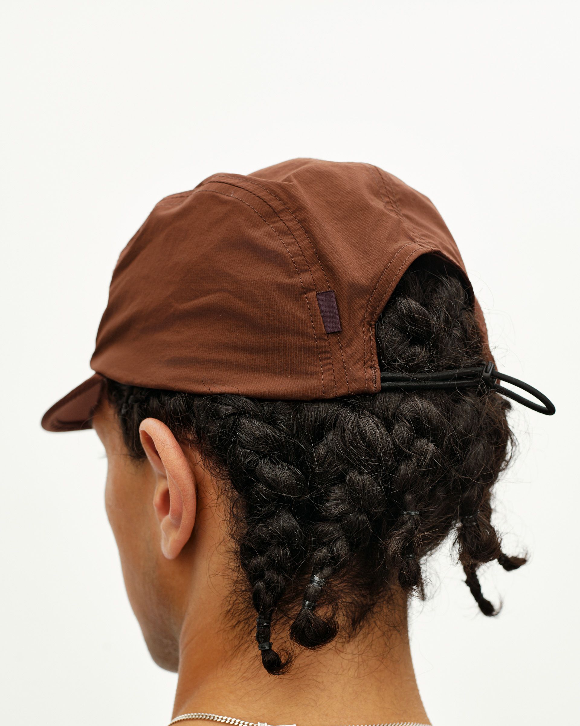 Maroon Brown Balance cycling cap on model, rear view with drawcord adjuster and woven tab