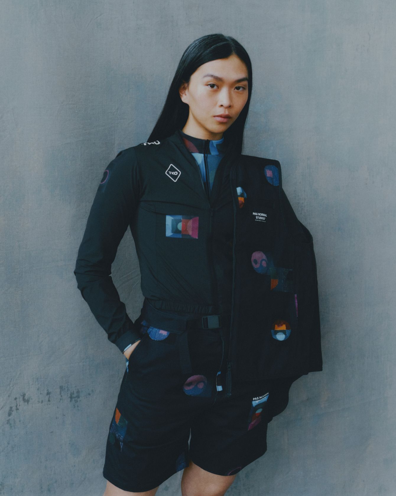 Model wearing Women's T.K.O. black cycling jacket with colorful geometric patches in studio shot