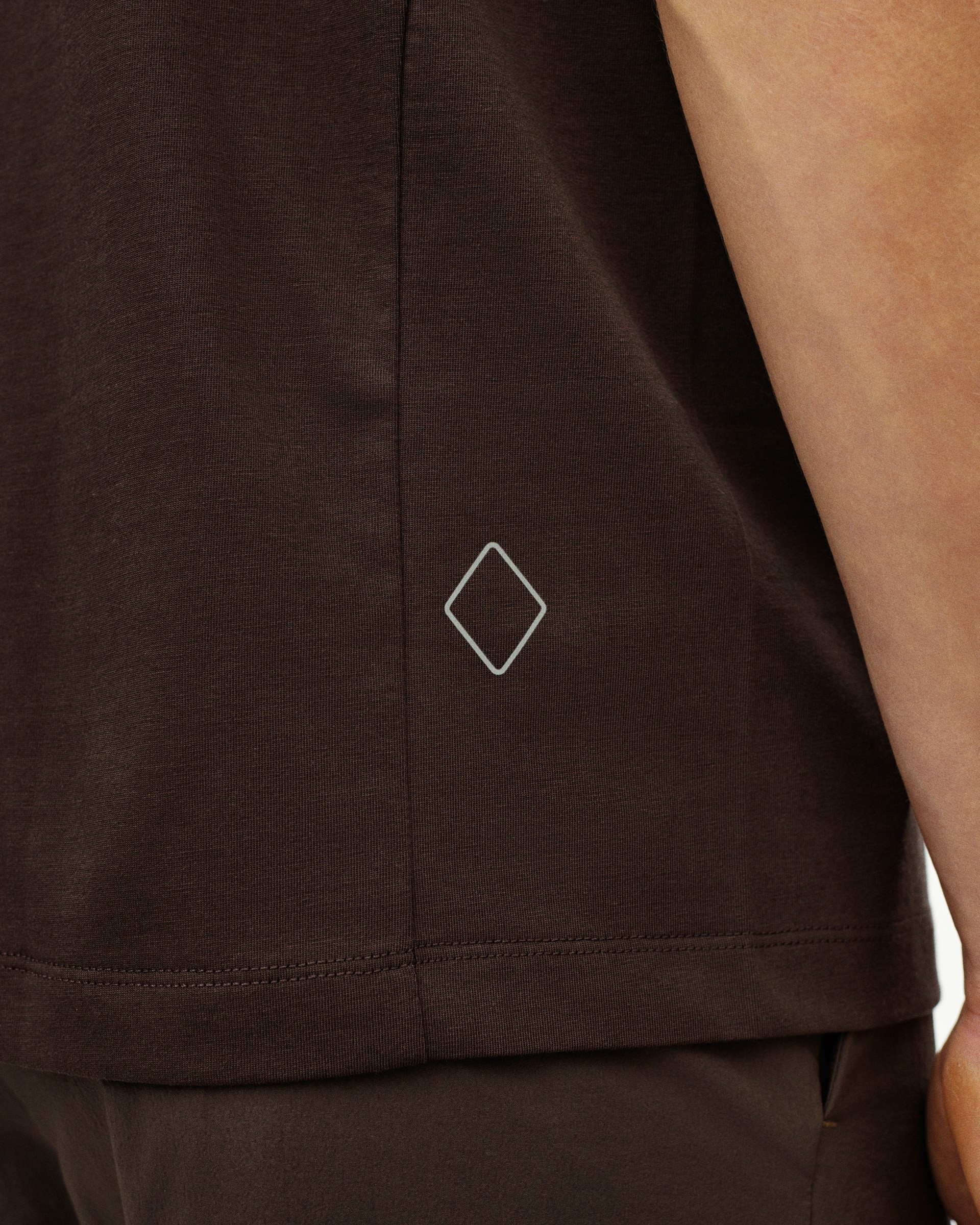 Dark Purple Off-Race Cotton Tech t-shirt, detail view showing white diamond logo on hem