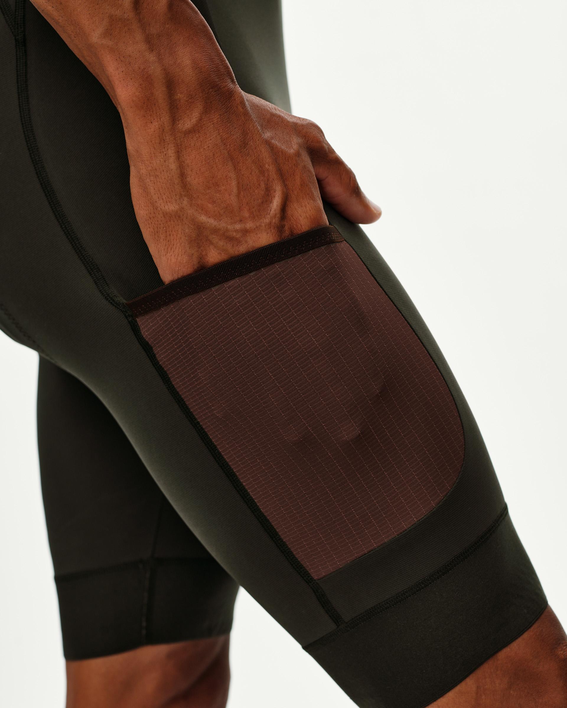 Dark Olive Escapism Cargo Bibs on model, thigh detail view with contrast ripstop cargo pocket