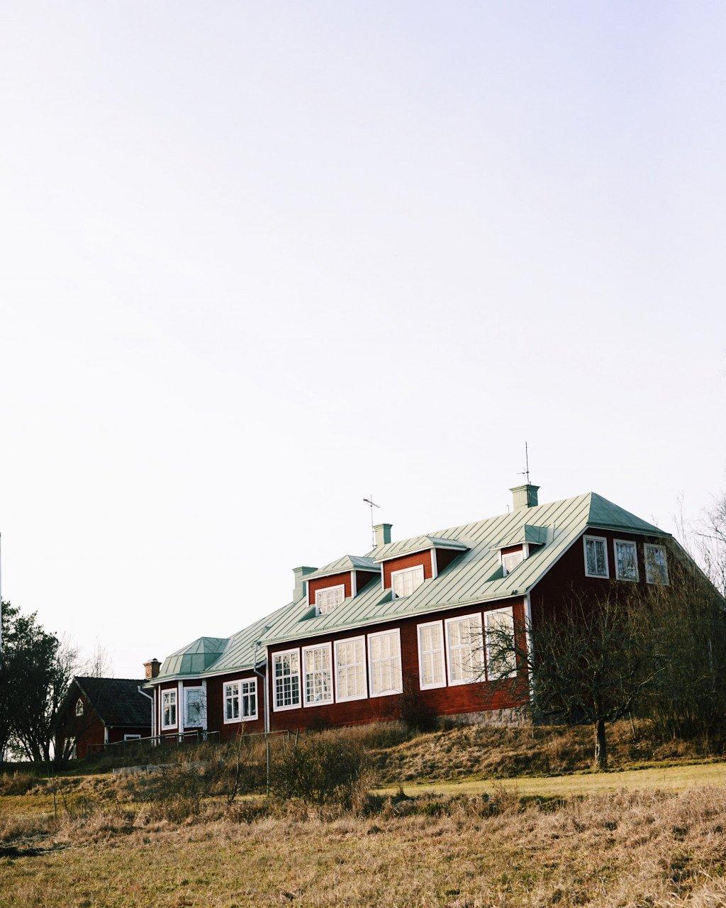 Traditional Swedish red wooden house with green metal roof in rural countryside setting