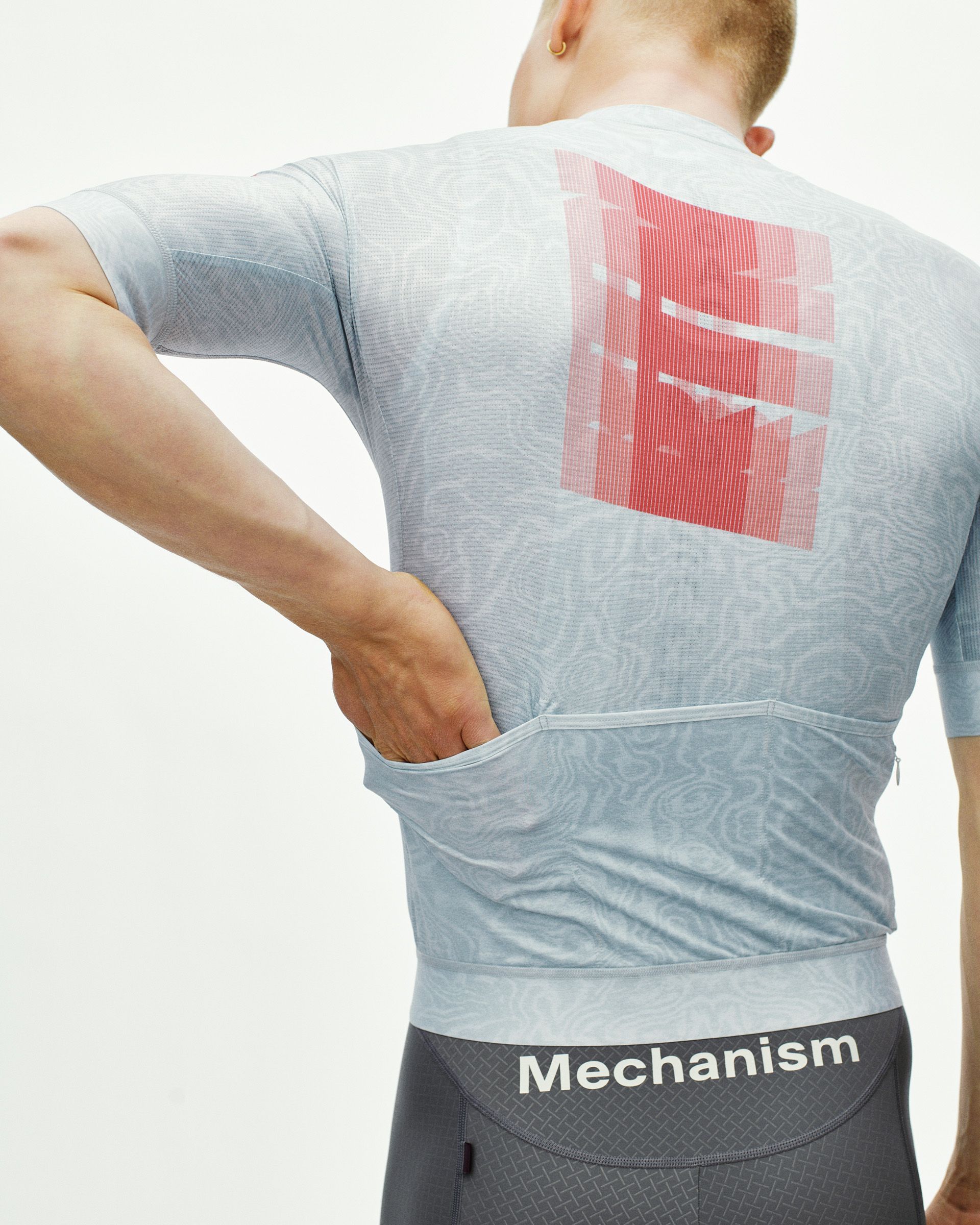 Light Blue Mechanism cycling jersey on model, rear view with red graphic back print and zip pocket