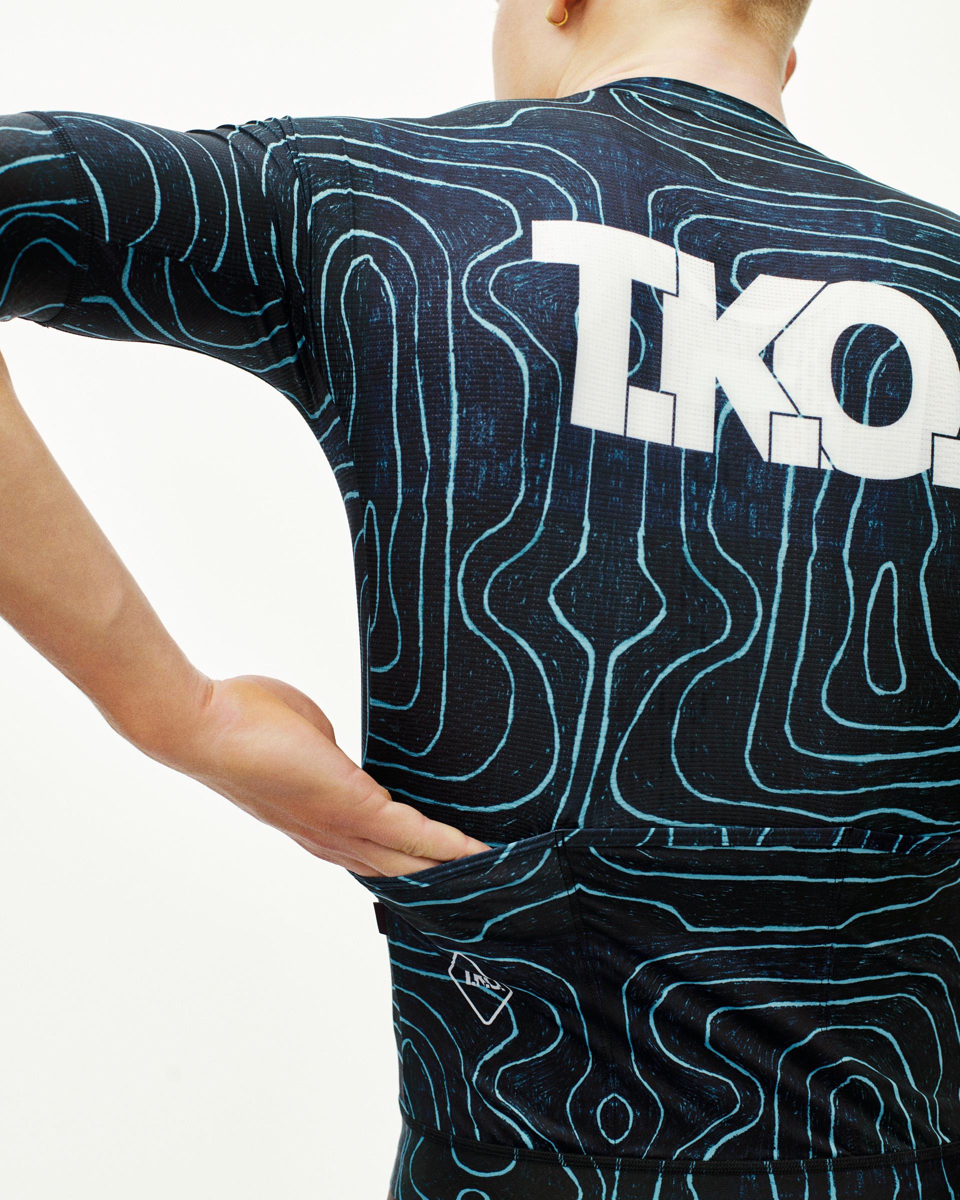 Blue T.K.O. Mechanism cycling jersey on model, rear view with topographic line print and white back logo