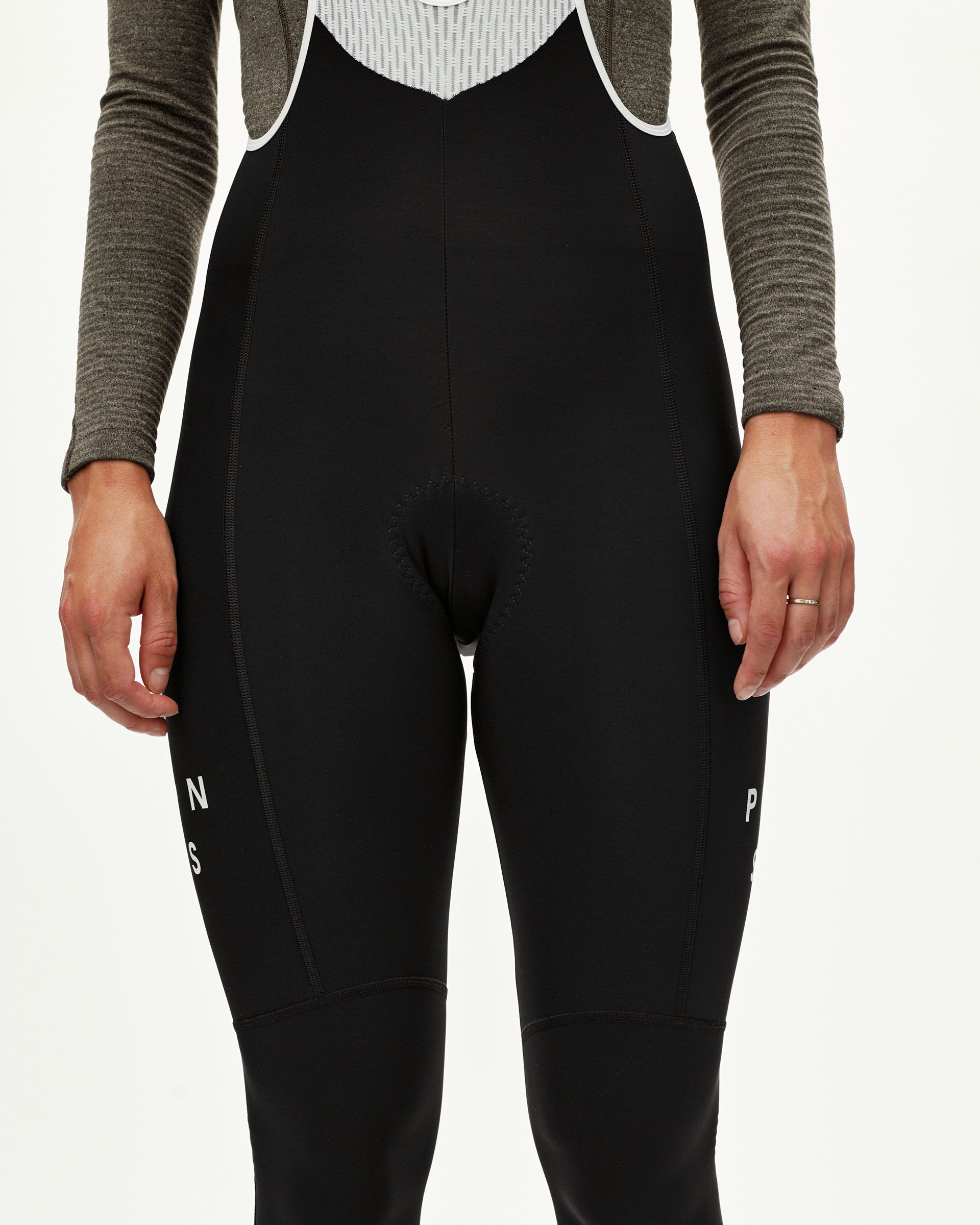 Black Mechanism women's thermal long cycling bibs, front view on model with white leg text detail