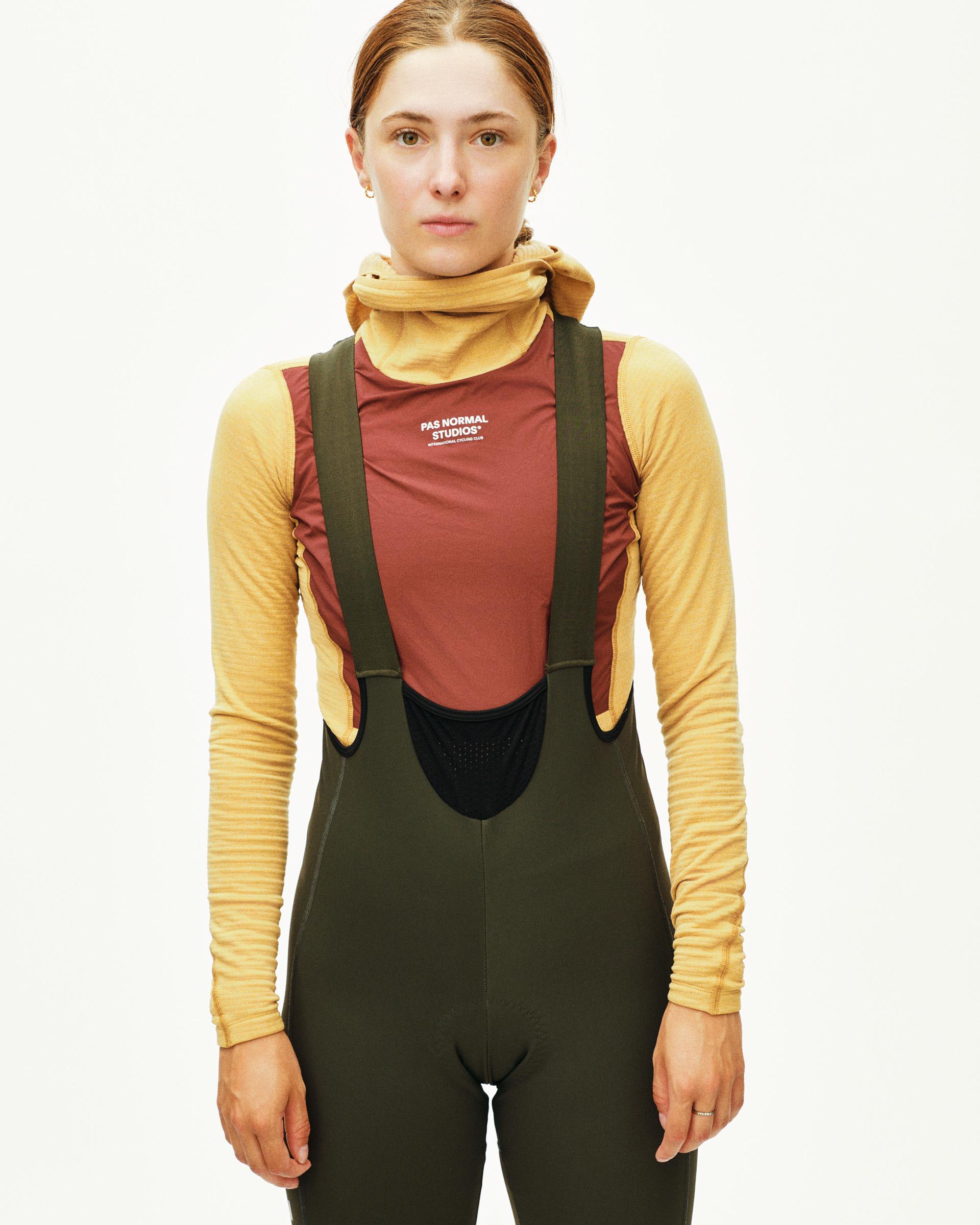Dark Olive Mechanism Deep Winter Long cycling bibs on model with high-cut bib panel and shoulder straps