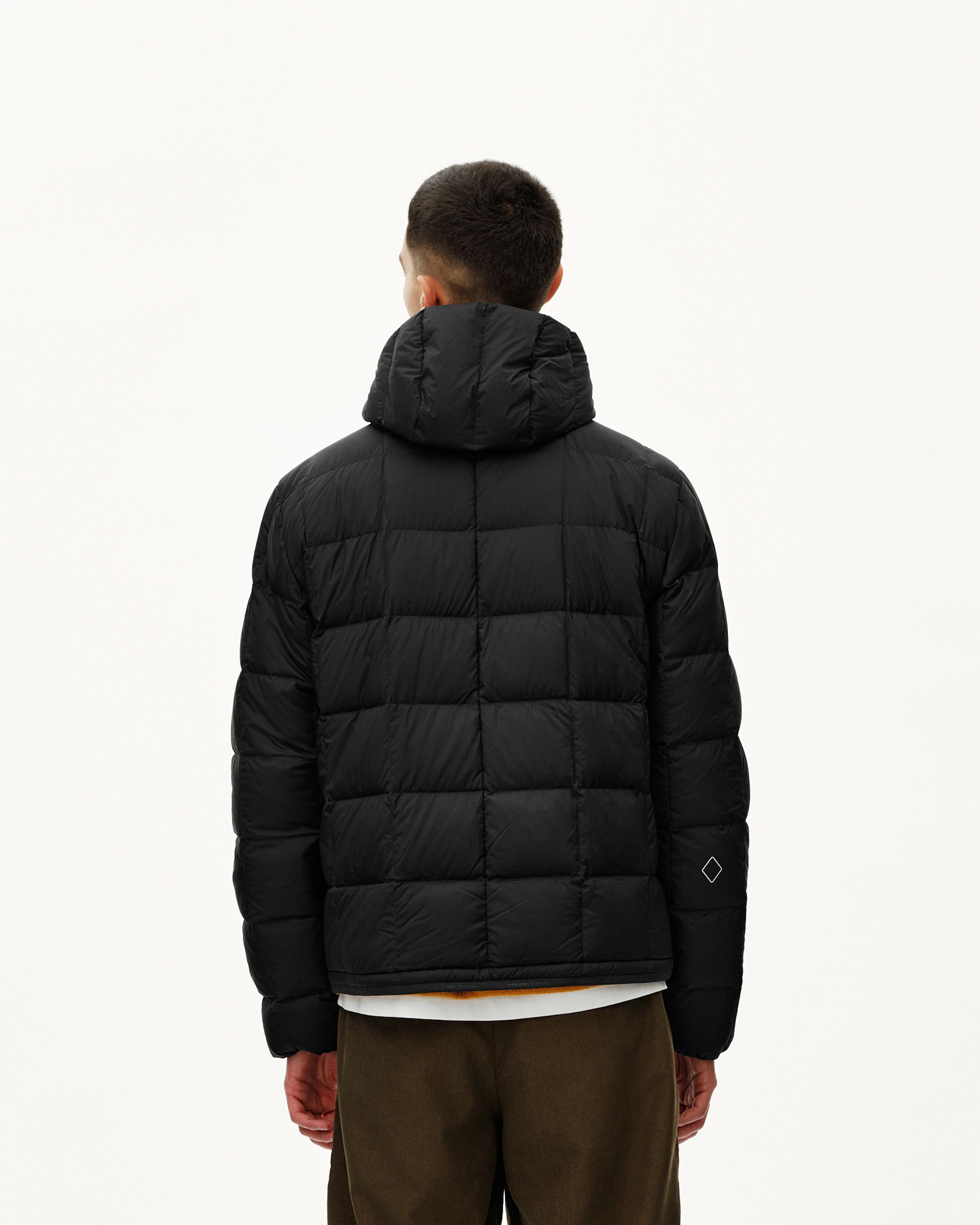 Black Off-Race Down Liner jacket on model, rear view with quilted panels and hood