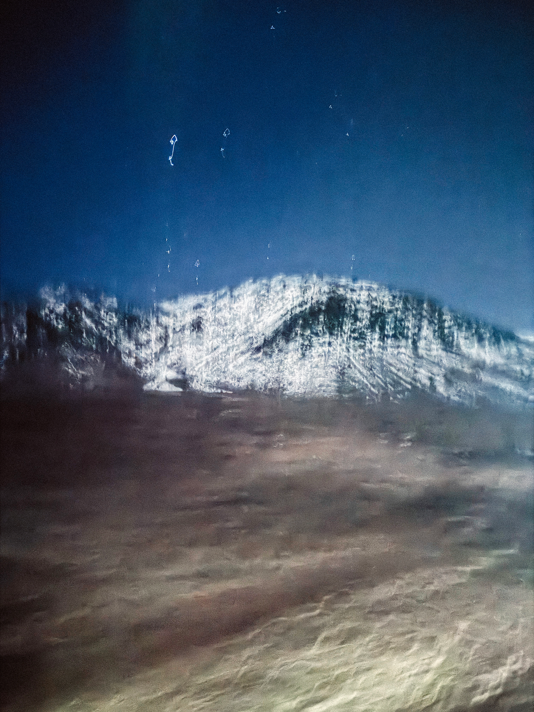 Snow-capped mountain peak under starry night sky with desert foreground