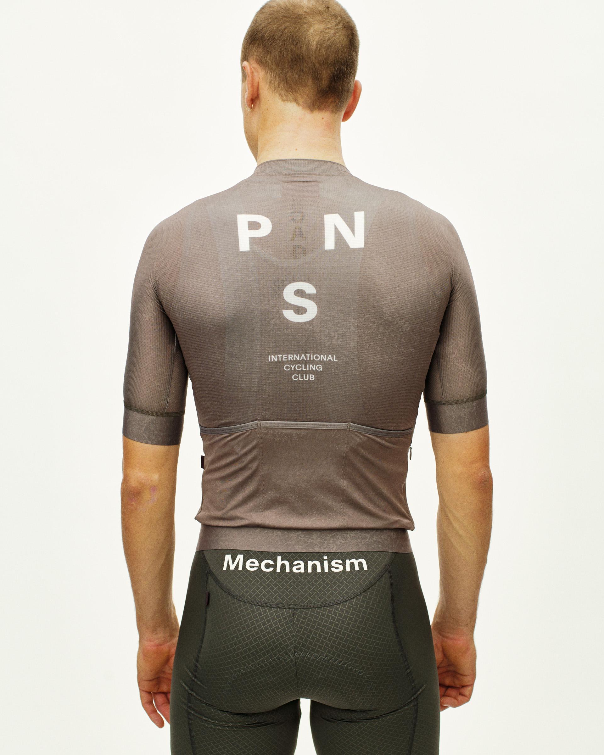 Brown Mechanism cycling jersey on model, rear view with white PNS logo and text