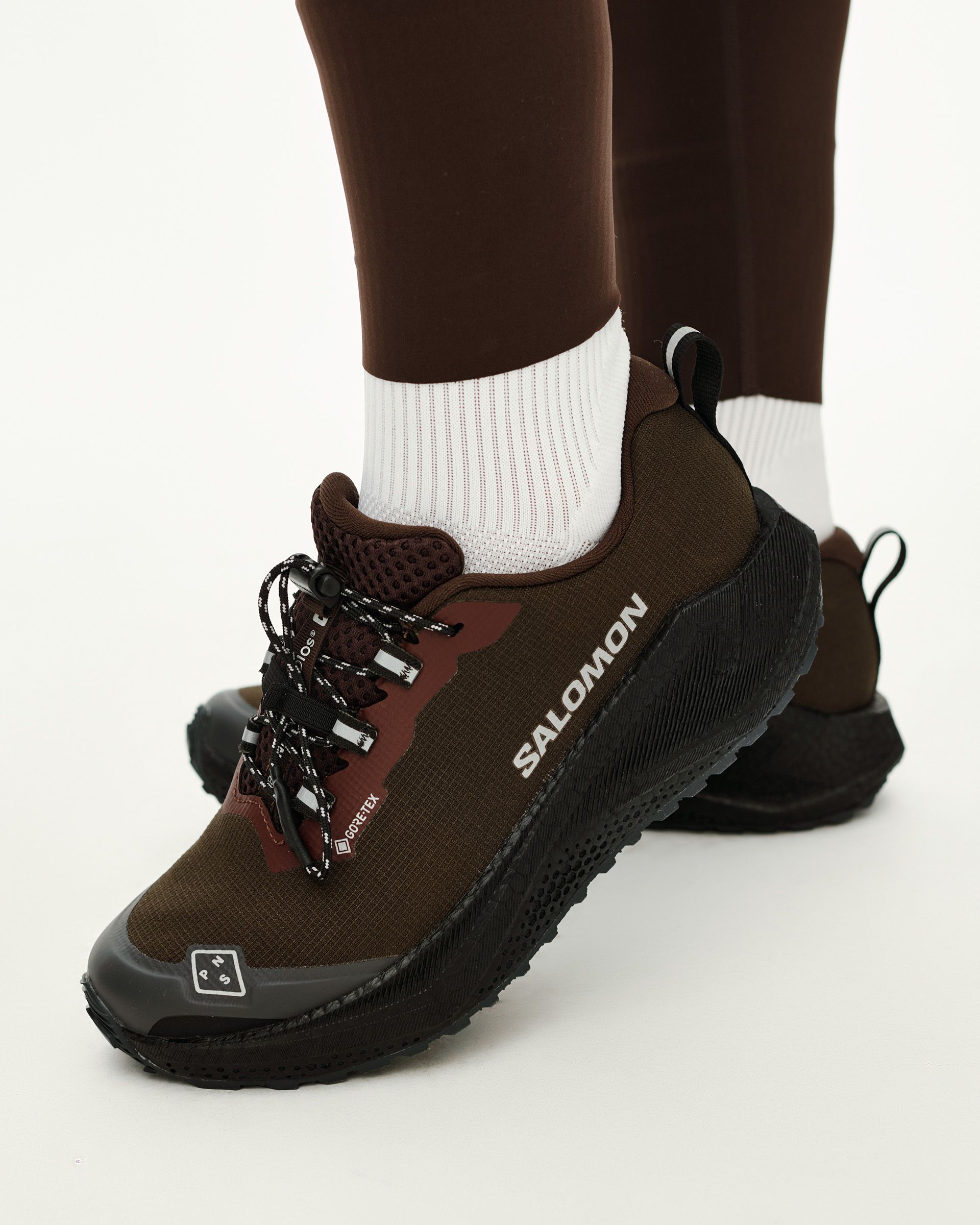 Light Brown Salomon AERO BLAZE 4 GRVL GTX trail shoe on model, side view with black chunky sole and contrast laces