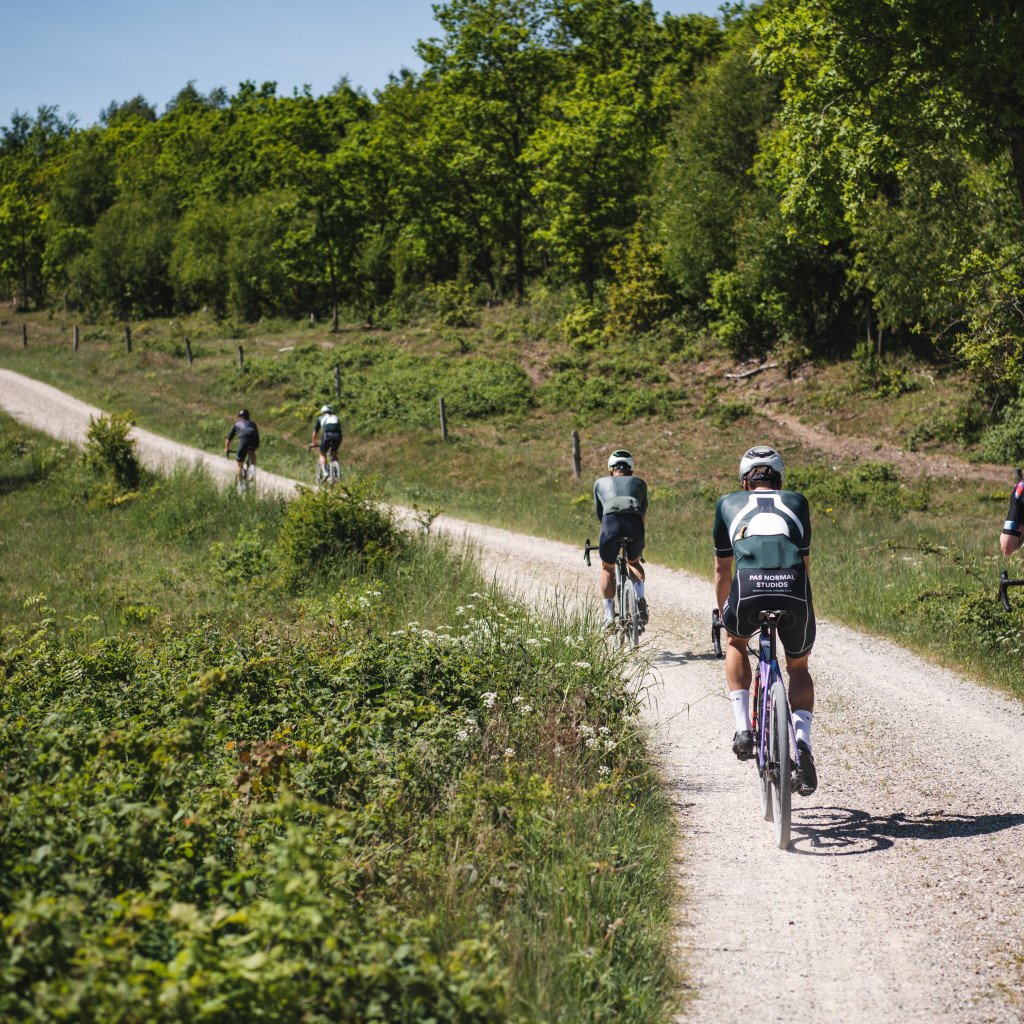 Cyclists riding on gravel path through countryside wearing cycling apparel