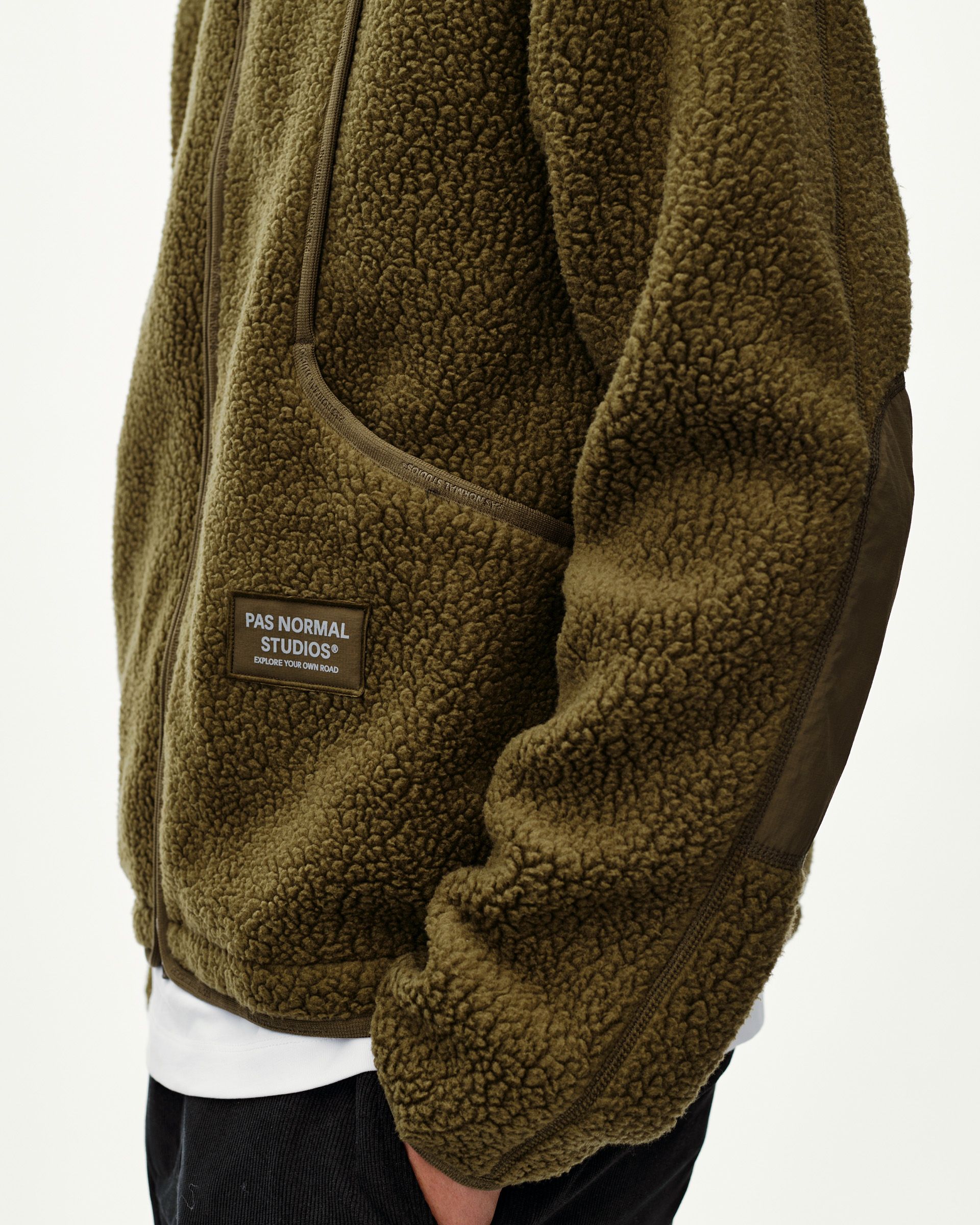 Deep Olive Off-Race Pile Fleece jacket, side detail on model with zip pocket and branded patch
