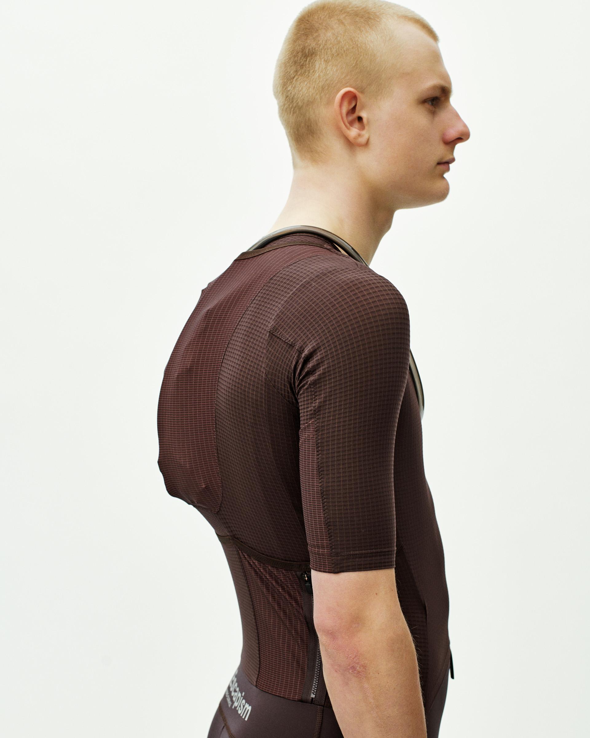 Dark Red Escapism speedsuit on model, side view with textured fabric and contrast trim