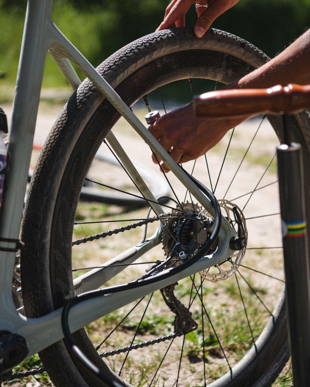 Close-up of bicycle wheel with hand adjusting tire, showing disc brake and drivetrain components