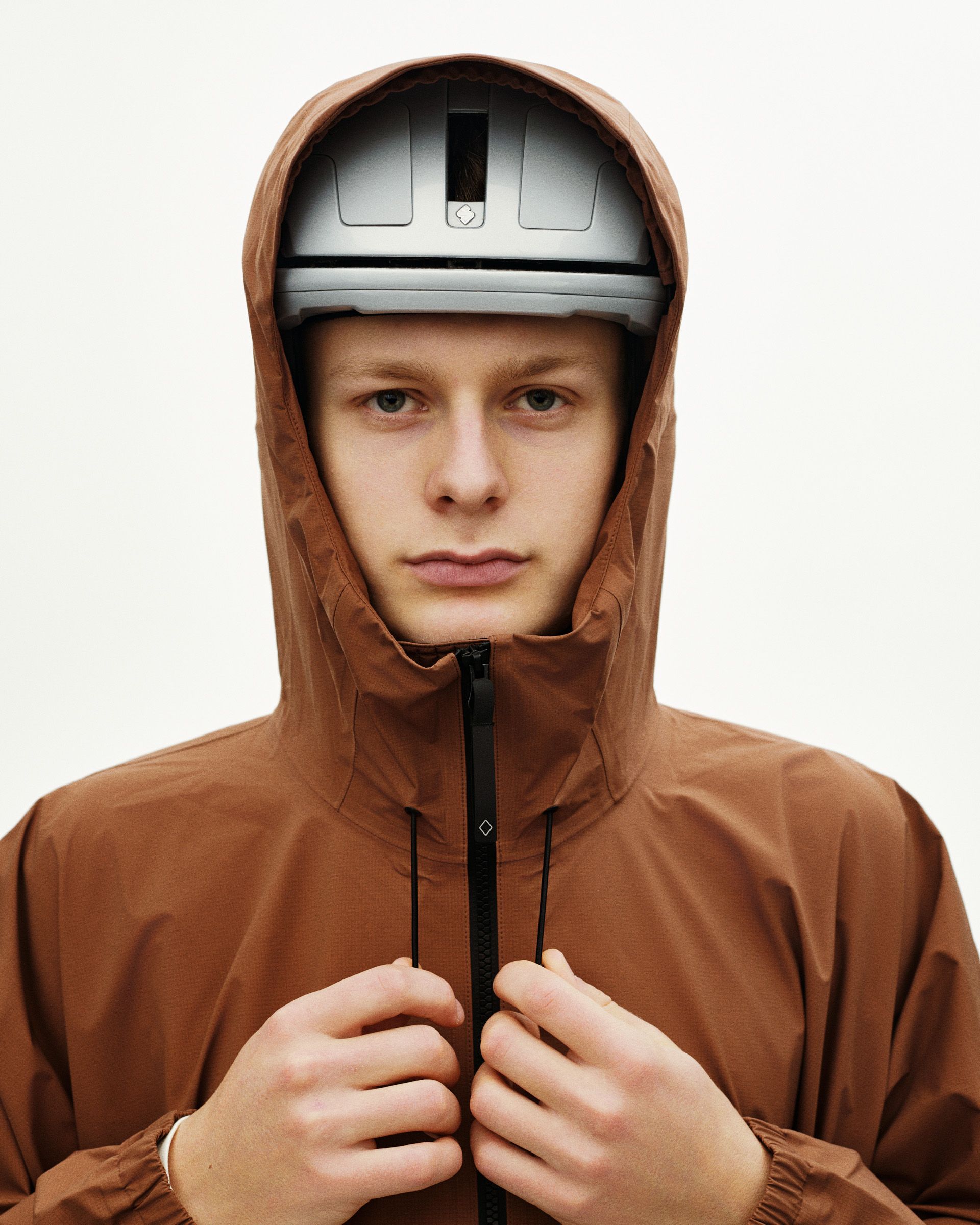 Brown Off-Race 3L Poncho on model with cycling helmet and hood up