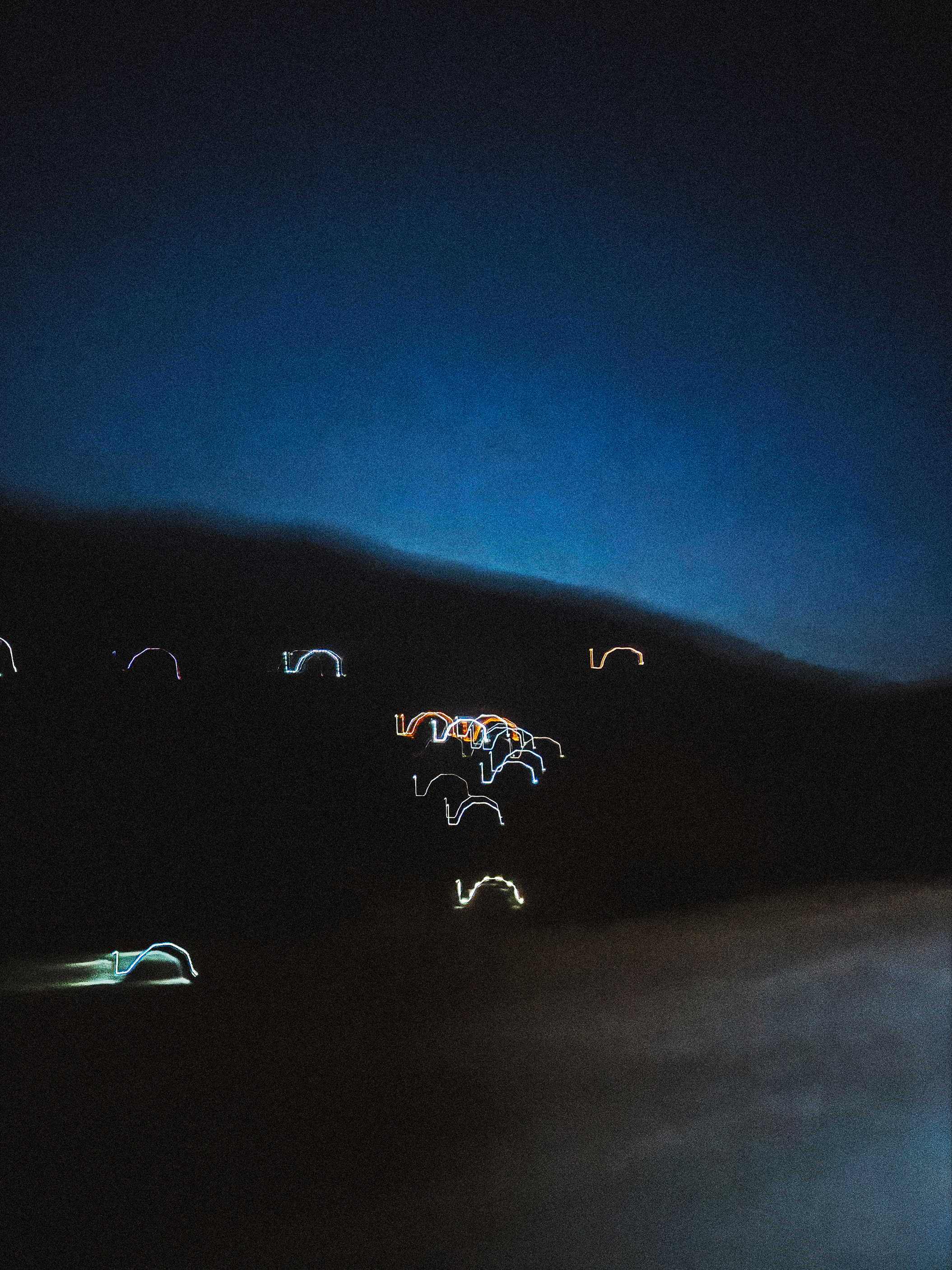 Cyclists with lights riding through mountainous terrain at dusk