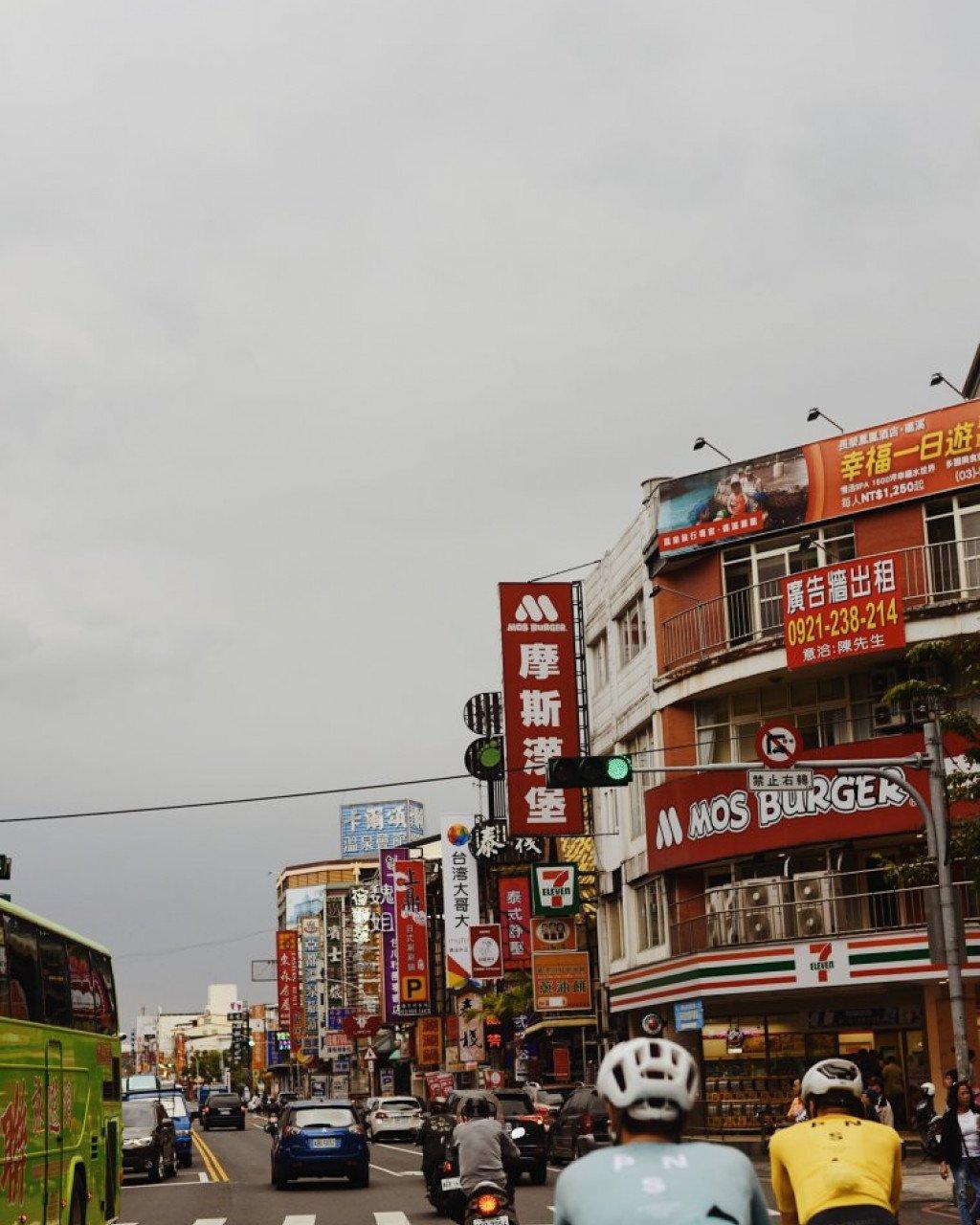 Cyclists on busy street with colorful signage in Asian city