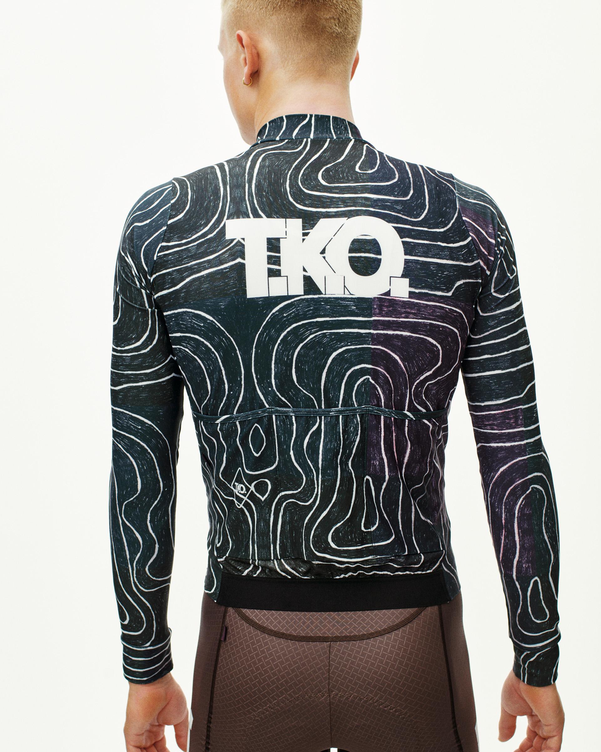 Black Multi T.K.O. Mechanism long sleeve cycling jersey on model, rear view with topographic all-over print and white logo