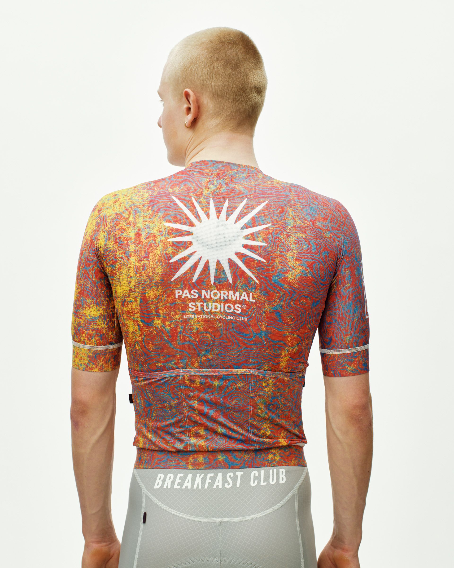 Breakfast Club Mechanism cycling jersey on model, rear view with multicolor AOP print and white sun logo