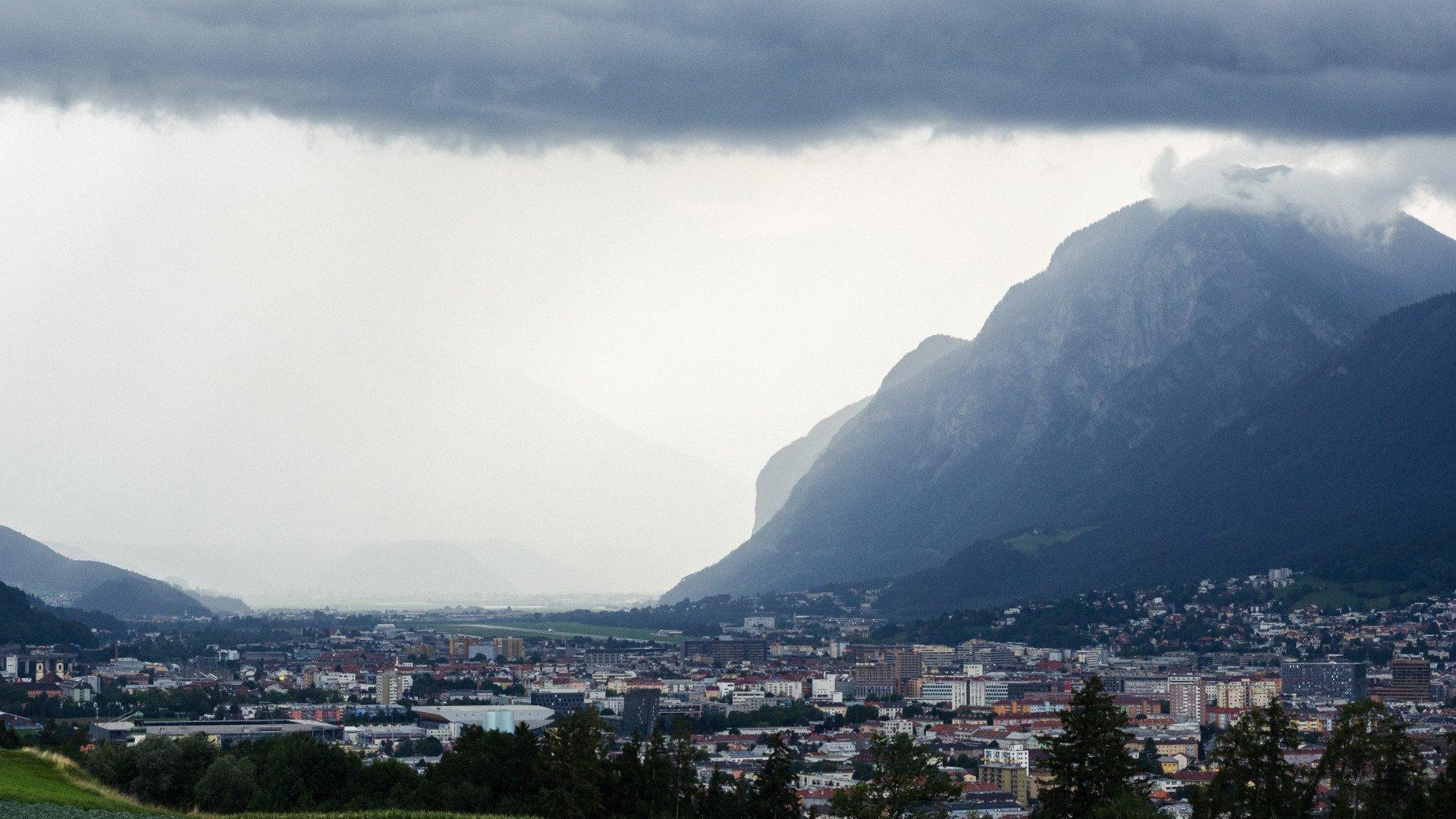 Mountain town view with dramatic cloudy sky over urban landscape