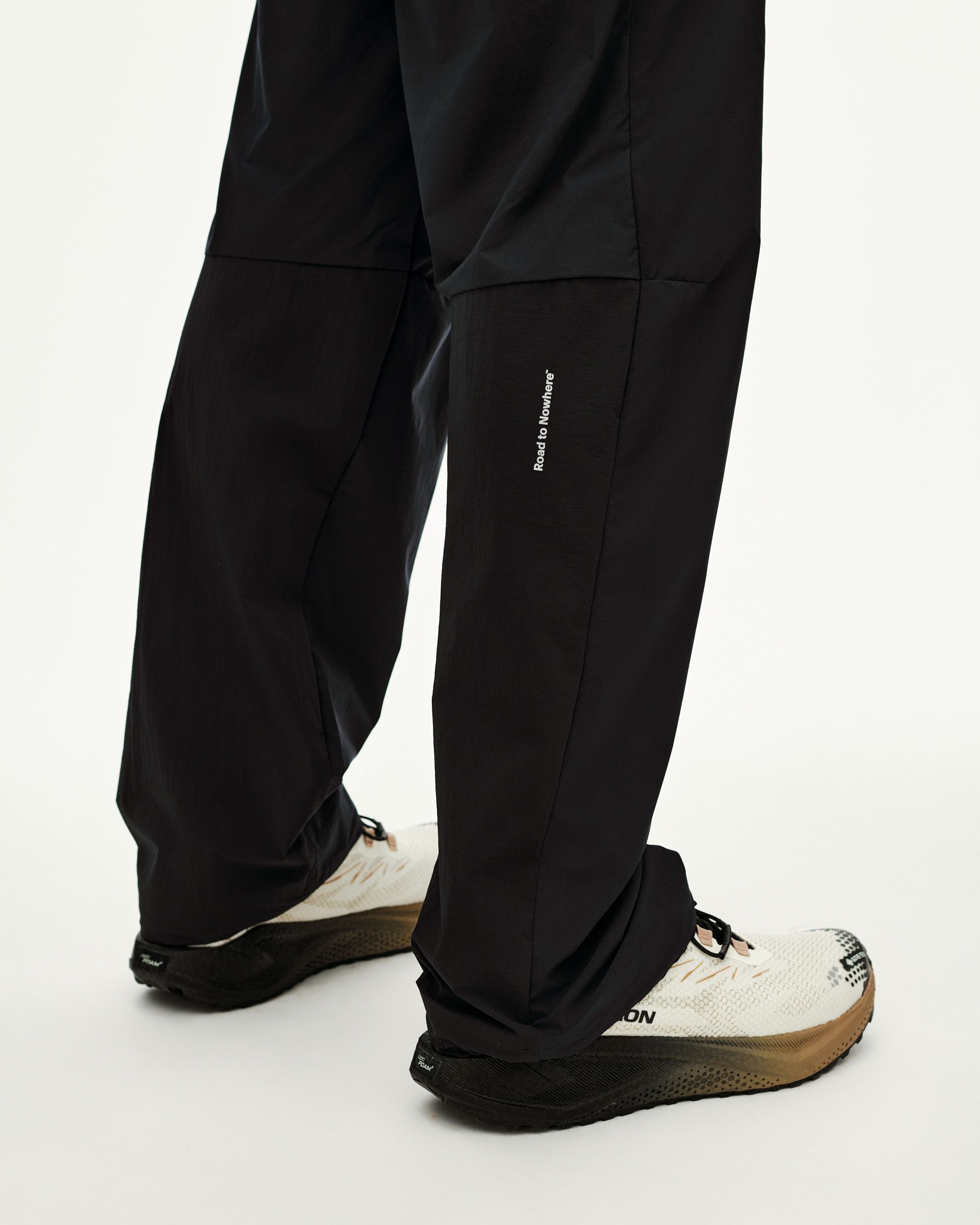 Black Balance Performance Pants on model, detail view of lower leg with small white text print