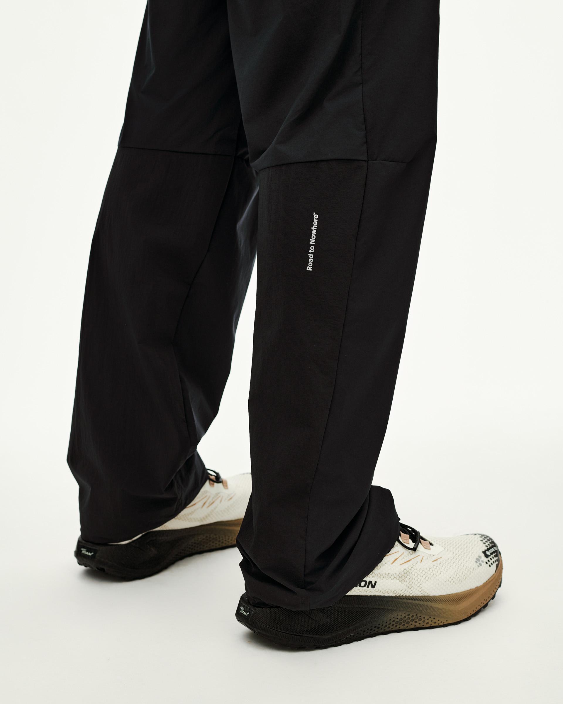 Black Balance Performance Pants on model, detail view of lower leg with small white text print