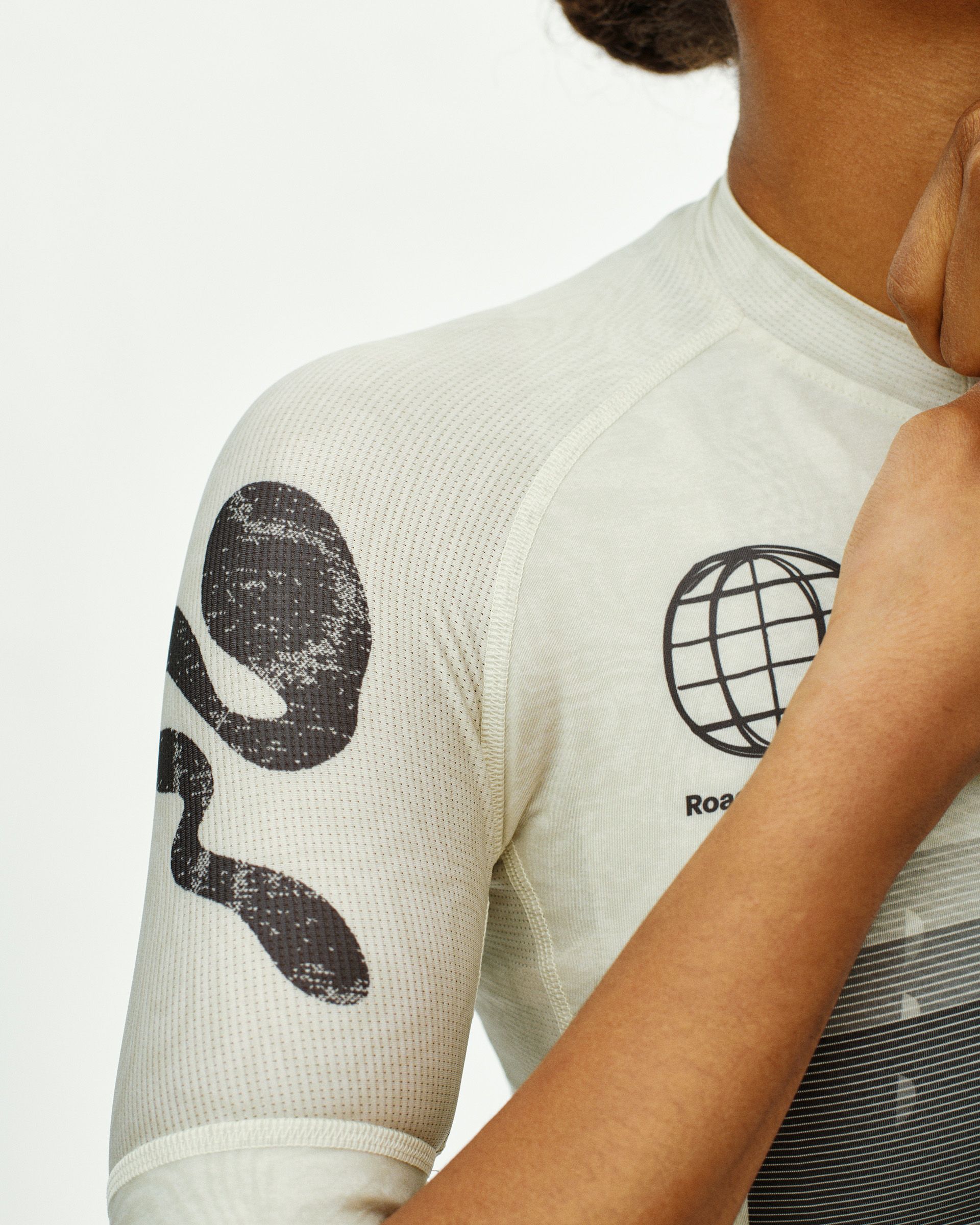 Off White Mechanism women's cycling jersey, detail view on model with globe graphic on chest and abstract sleeve print