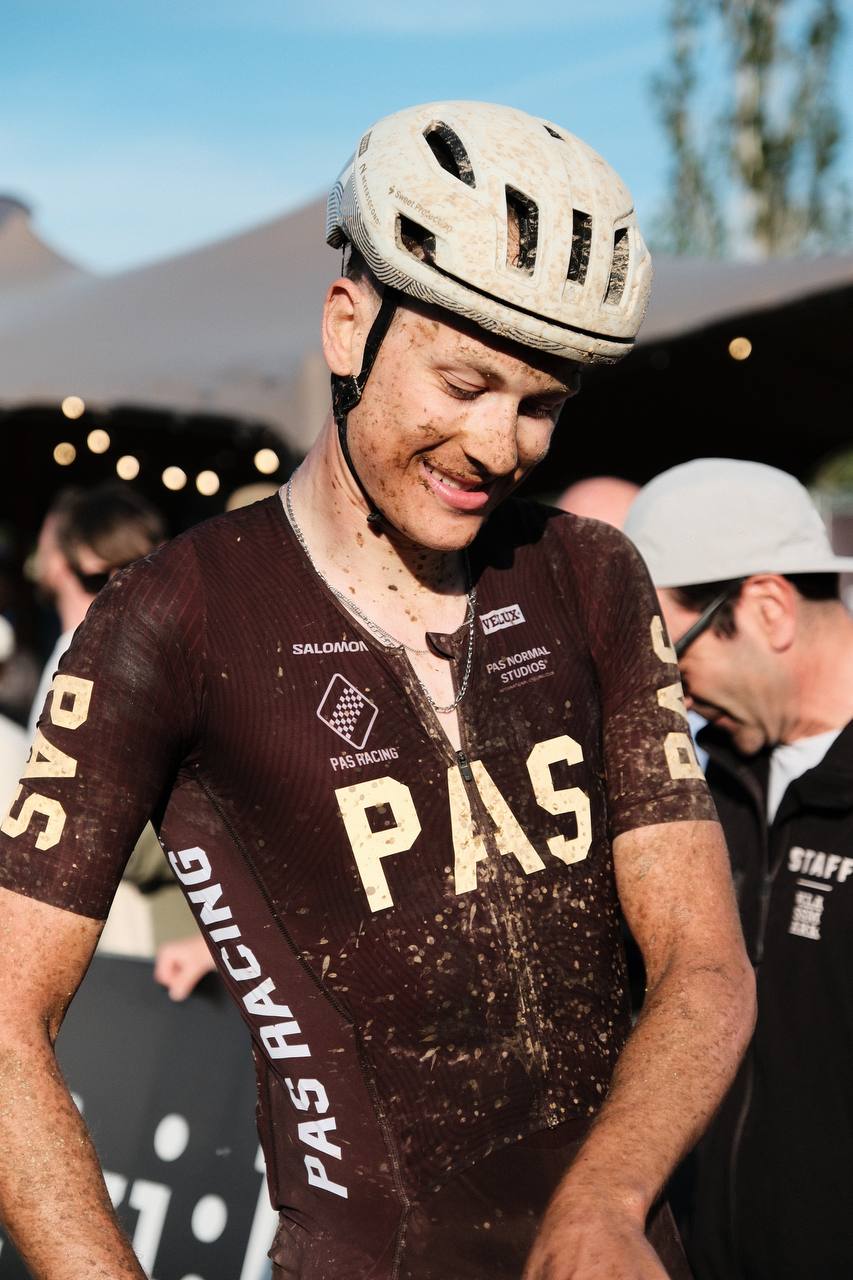 Model wearing brown PAS collection racing jersey with dirt after gravel race, helmet on