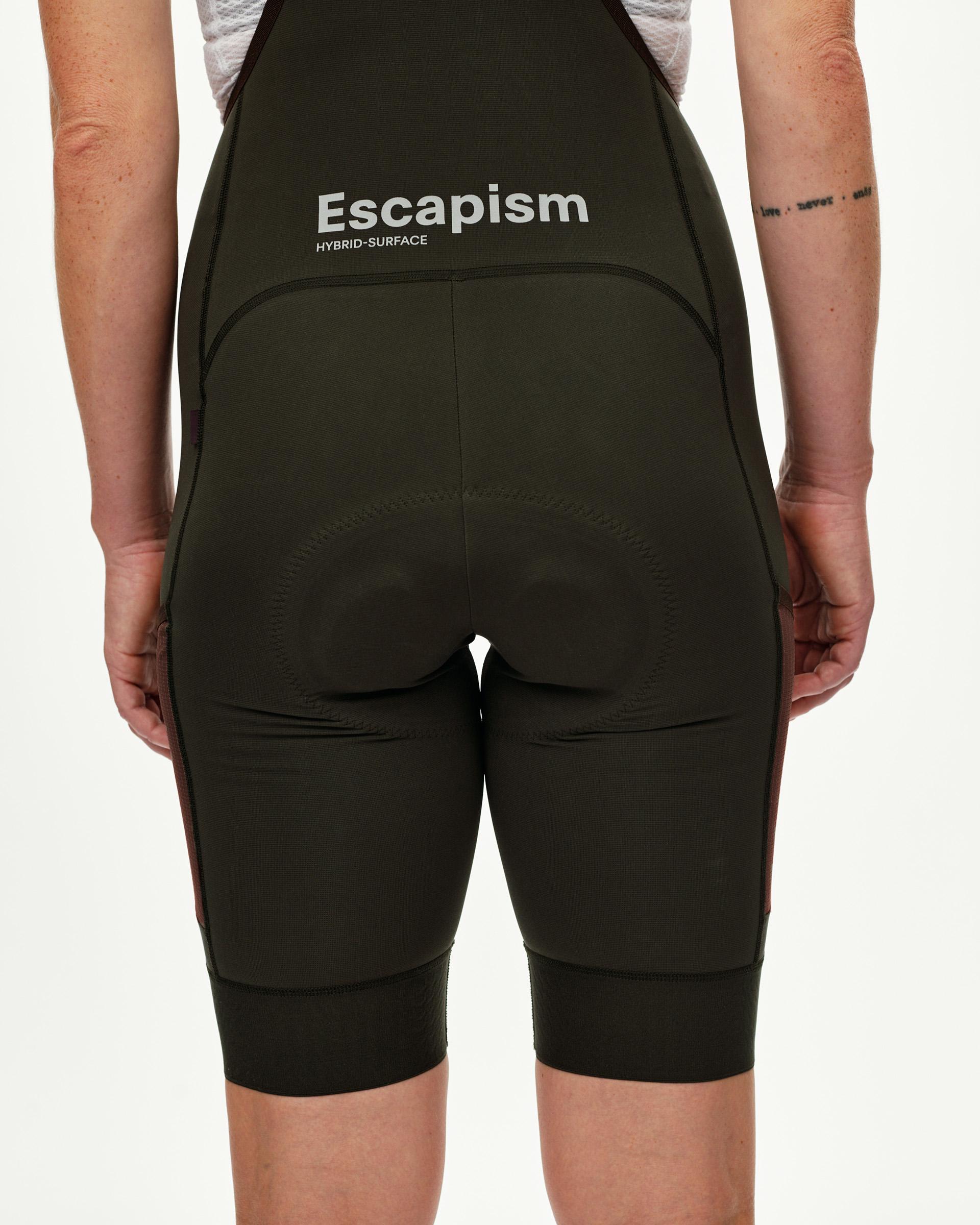 Dark Olive Escapism Cargo cycling bibs on model, rear view with Escapism logo print at waist