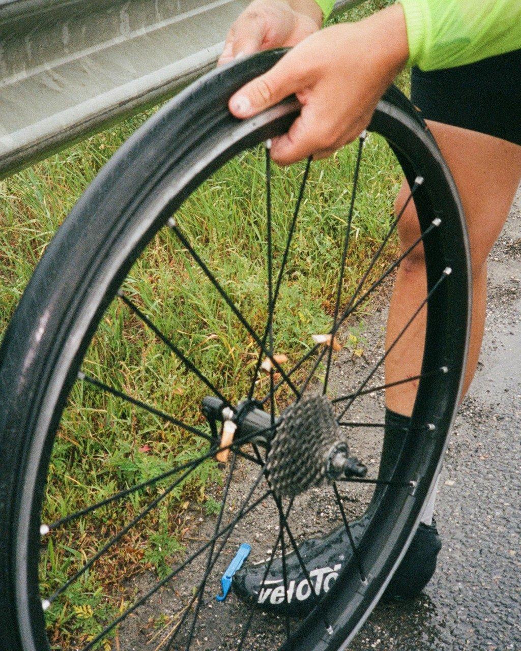 Cyclist in green jersey adjusting bicycle wheel on roadside