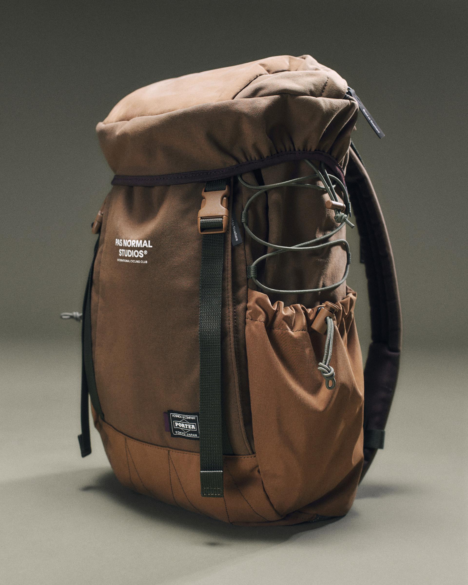 Light Brown Porter-Yoshida backpack, three-quarter view with roll-top closure, front strap, and elasticated side pocket