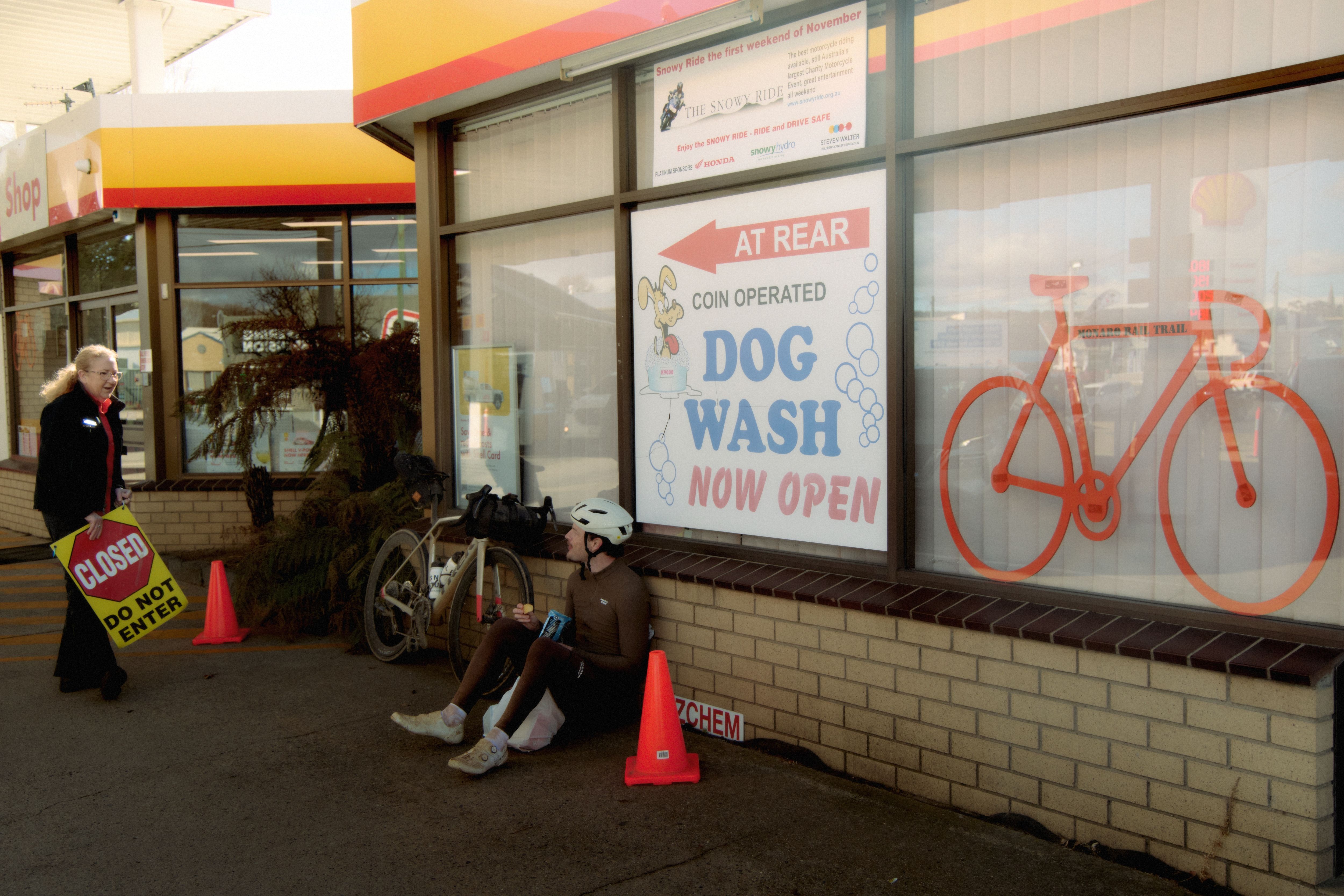 Cyclist resting outside shop window with bicycle after ride