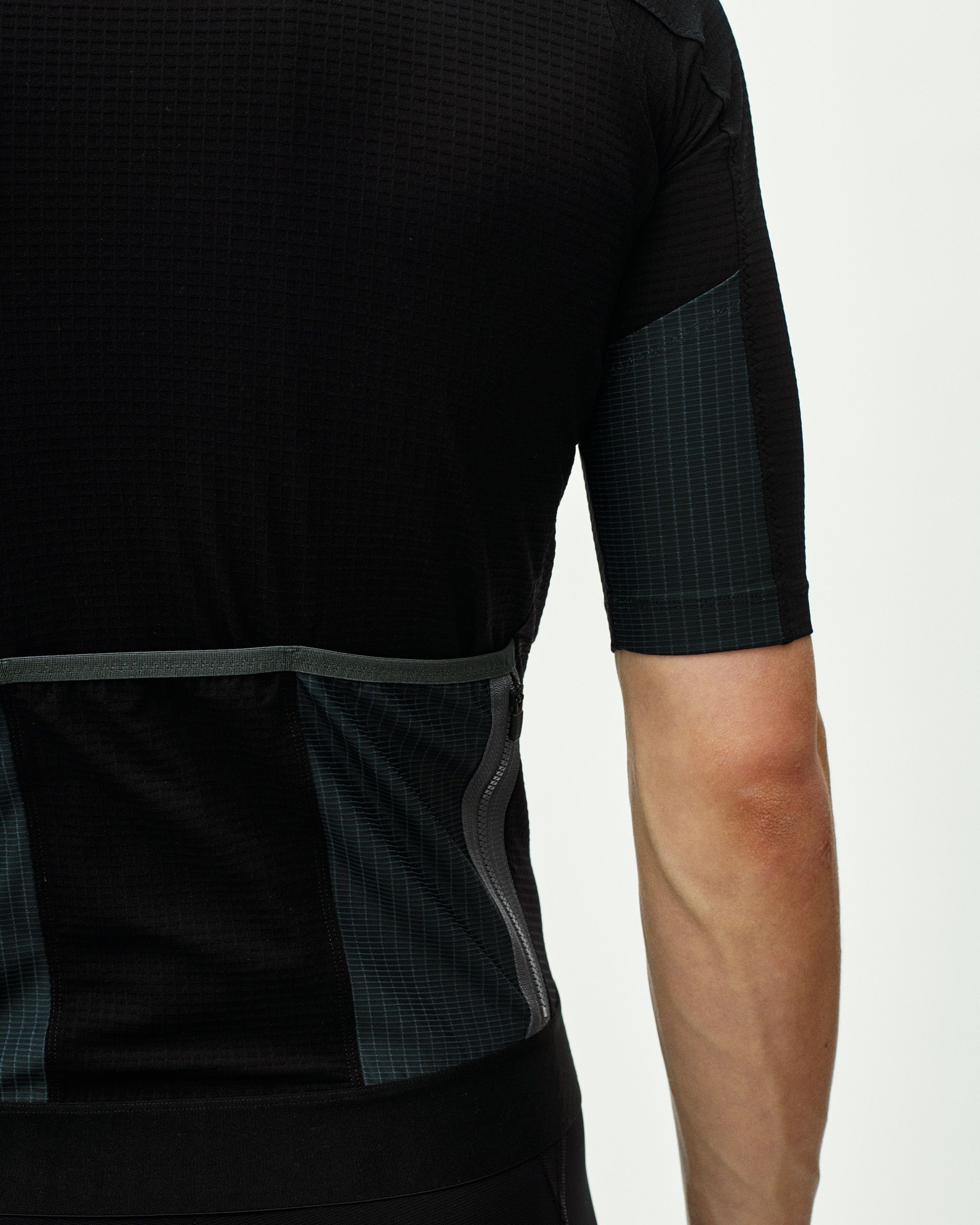 Black Escapism cycling jersey on model showing side panel with textured grid pattern and contrast trim