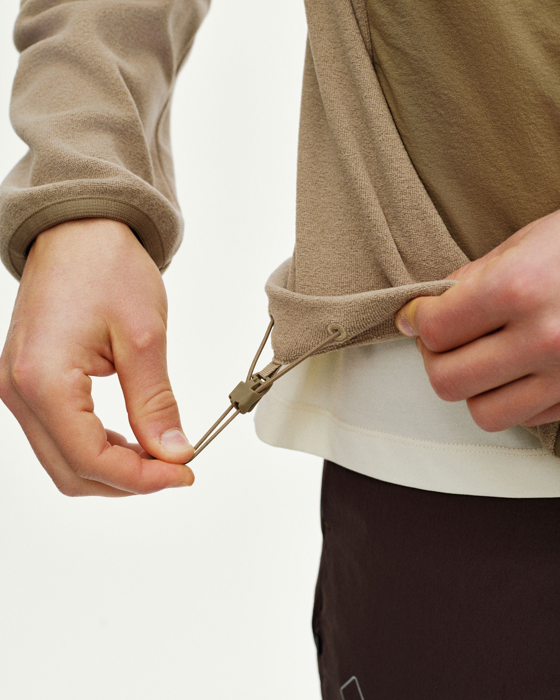 Beige Off-Race Light Fleece half-zip on model showing adjustable drawcord hem detail