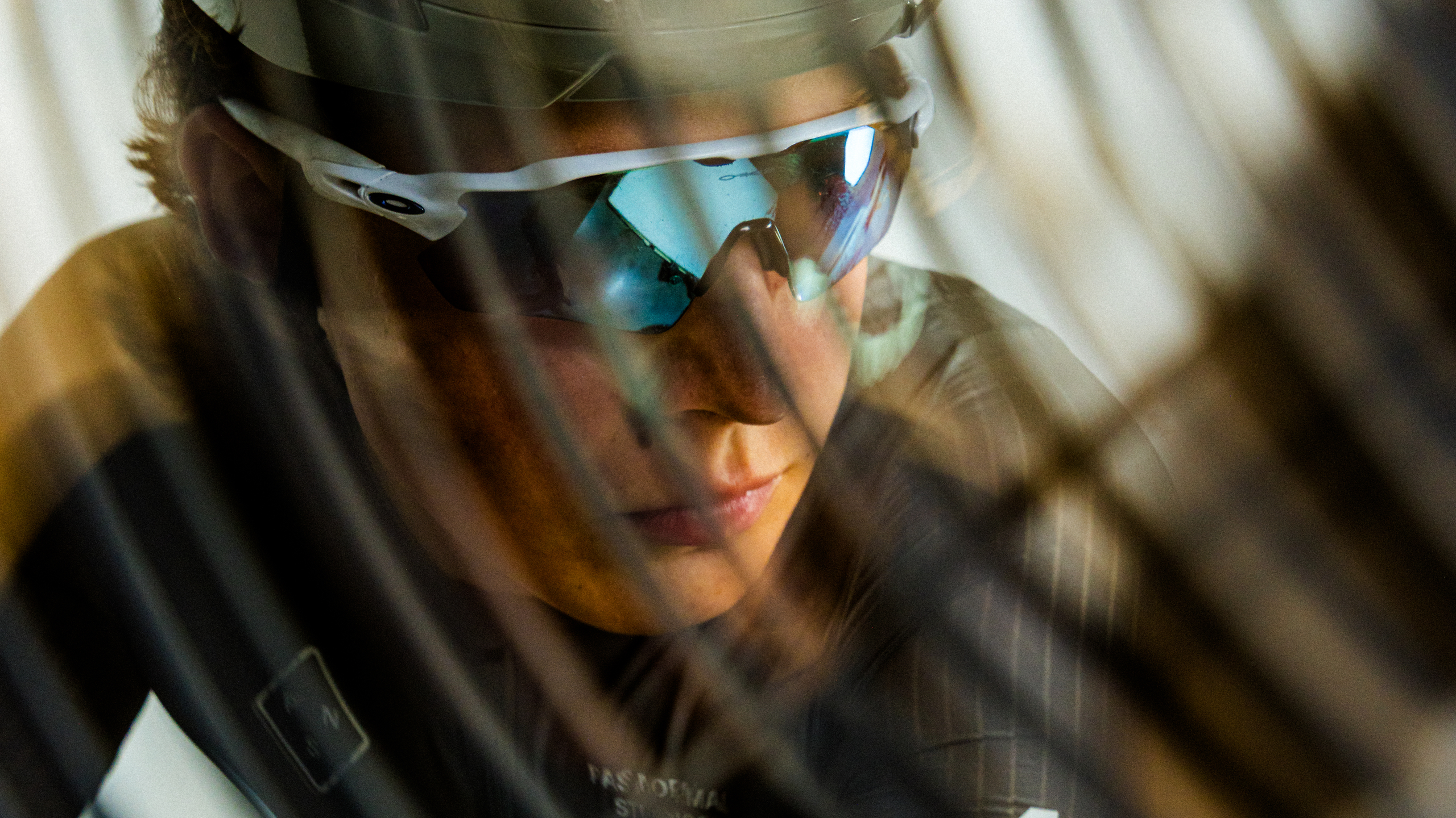 Model wearing cycling sunglasses with white frame and blue mirrored lenses in motion blur