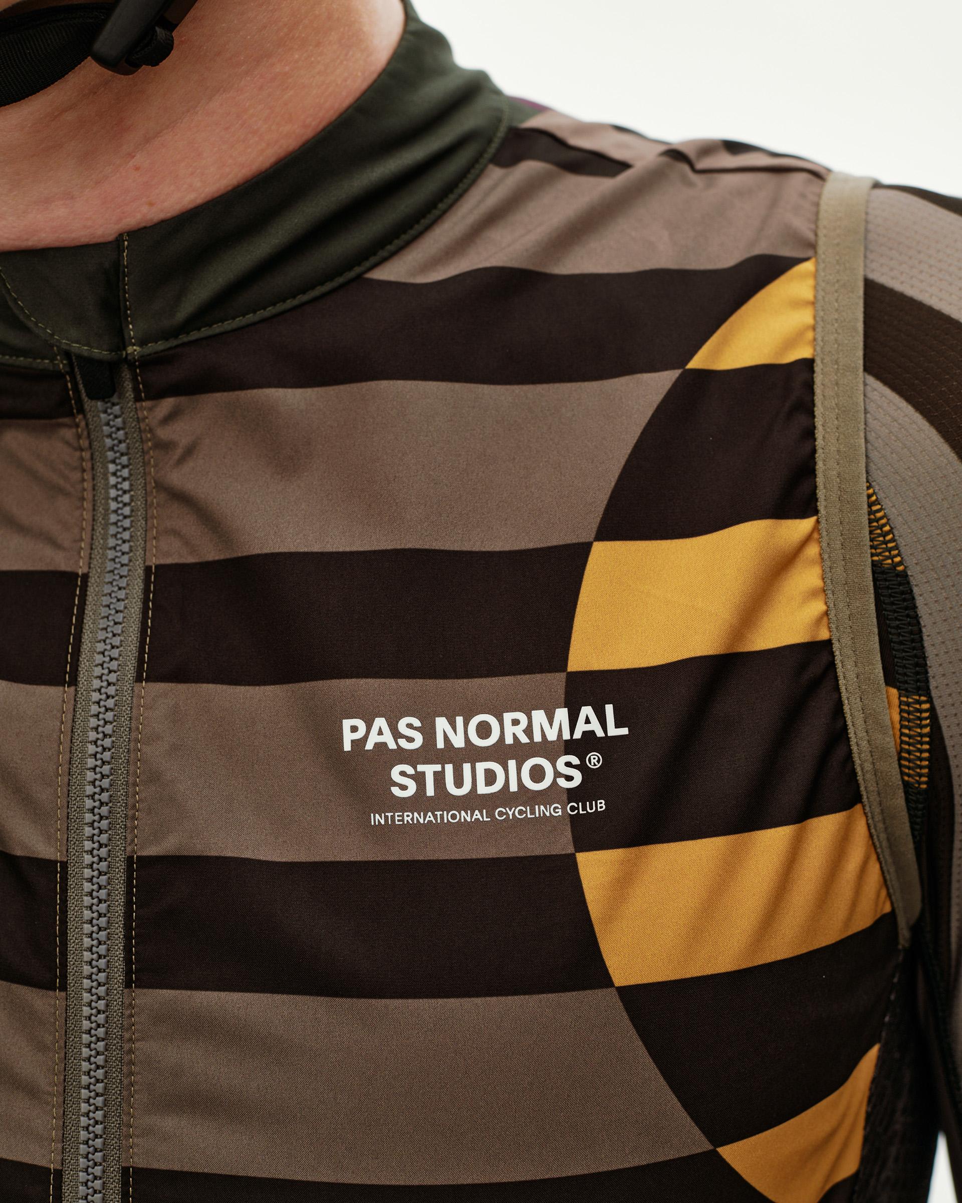 International Earth brown Mechanism Stow Away cycling gilet, front detail on model with striped AOP and gold arc print