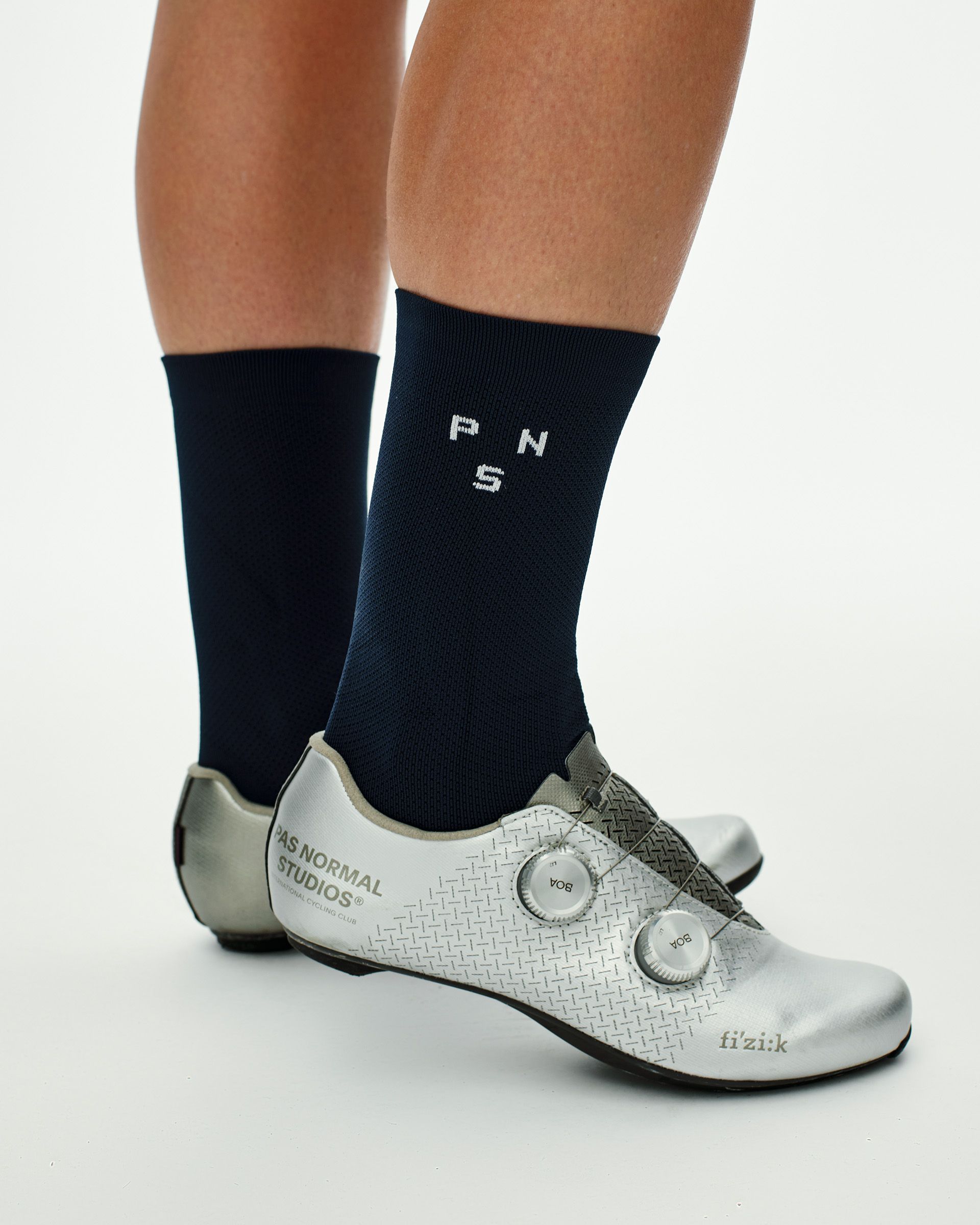 Navy Essential Race cycling socks on model, side view with white knit logo, worn with silver Fizik road shoes