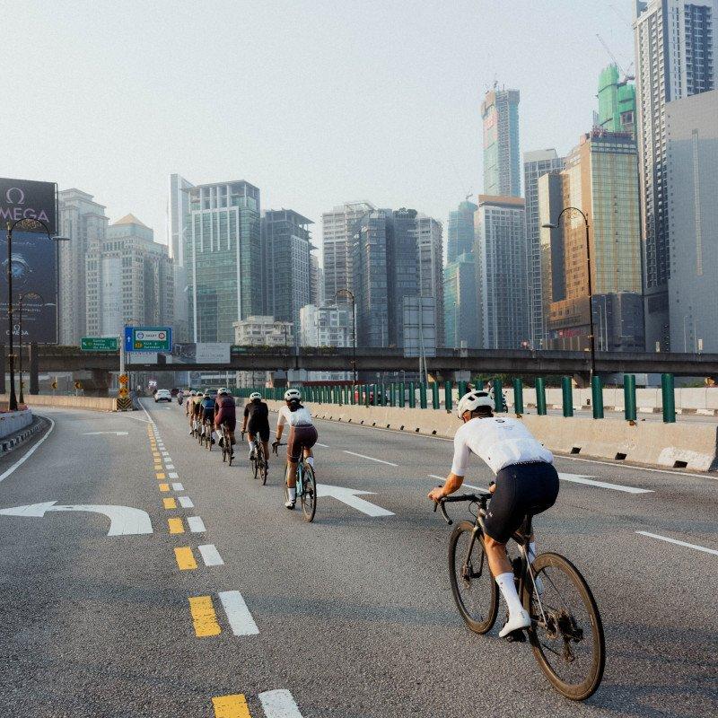 Cyclists riding in formation on urban highway with Singapore city skyline in background