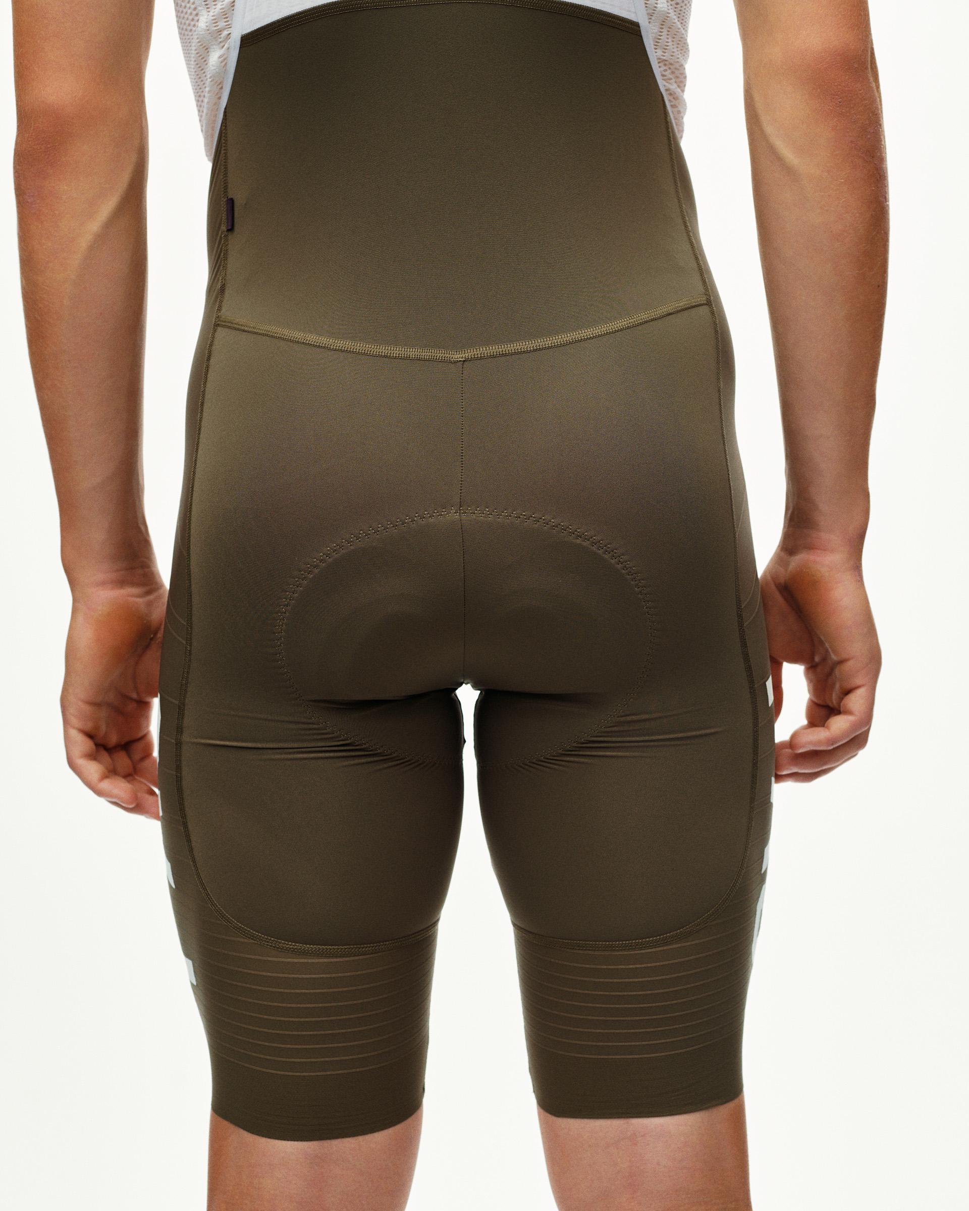 Dark Earth khaki PAS Mechanism Pro cycling bibs on model, rear view with padded seat panel and ribbed leg cuffs