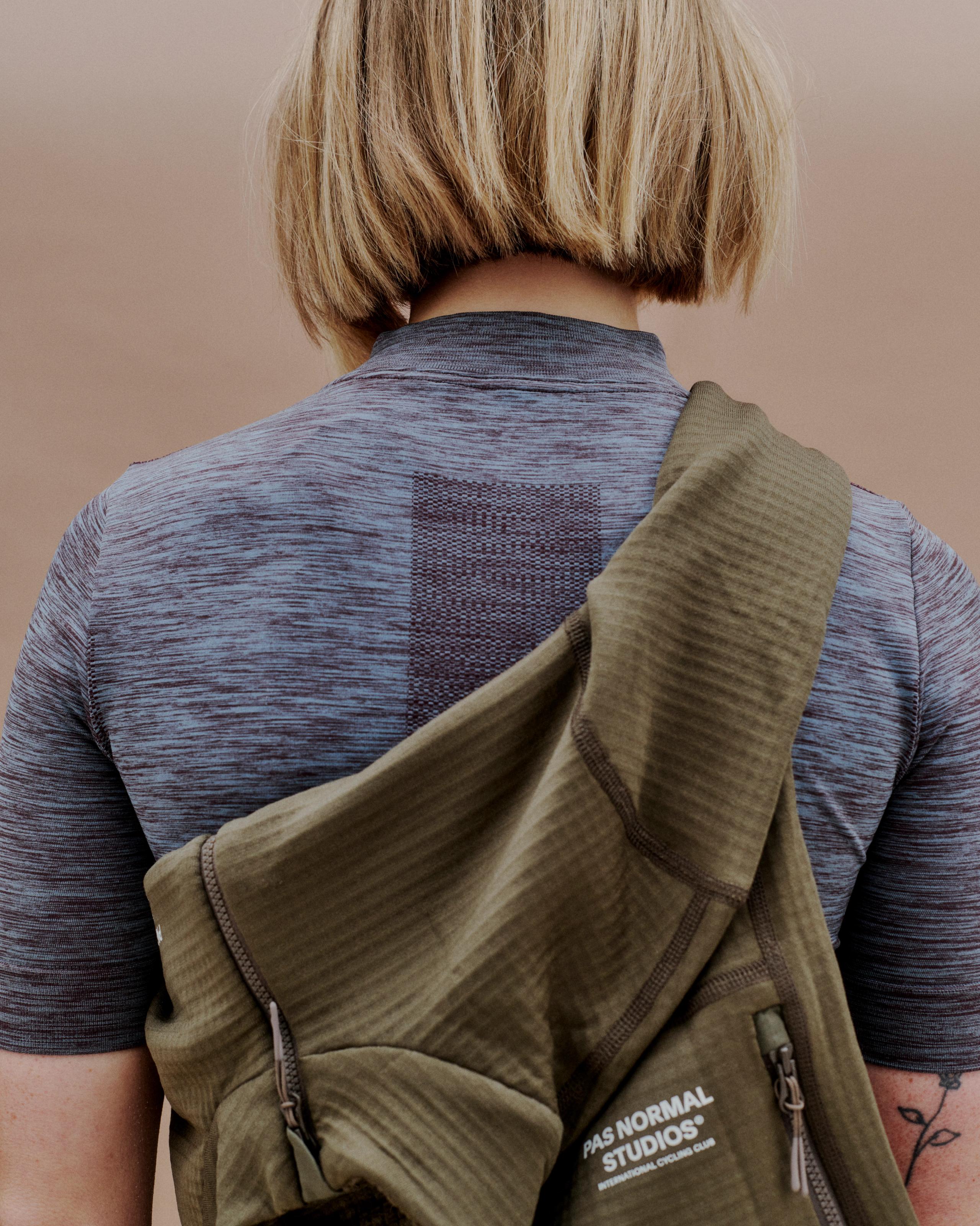 Model wearing grey marled jersey with mesh panel detail, olive jacket over shoulder