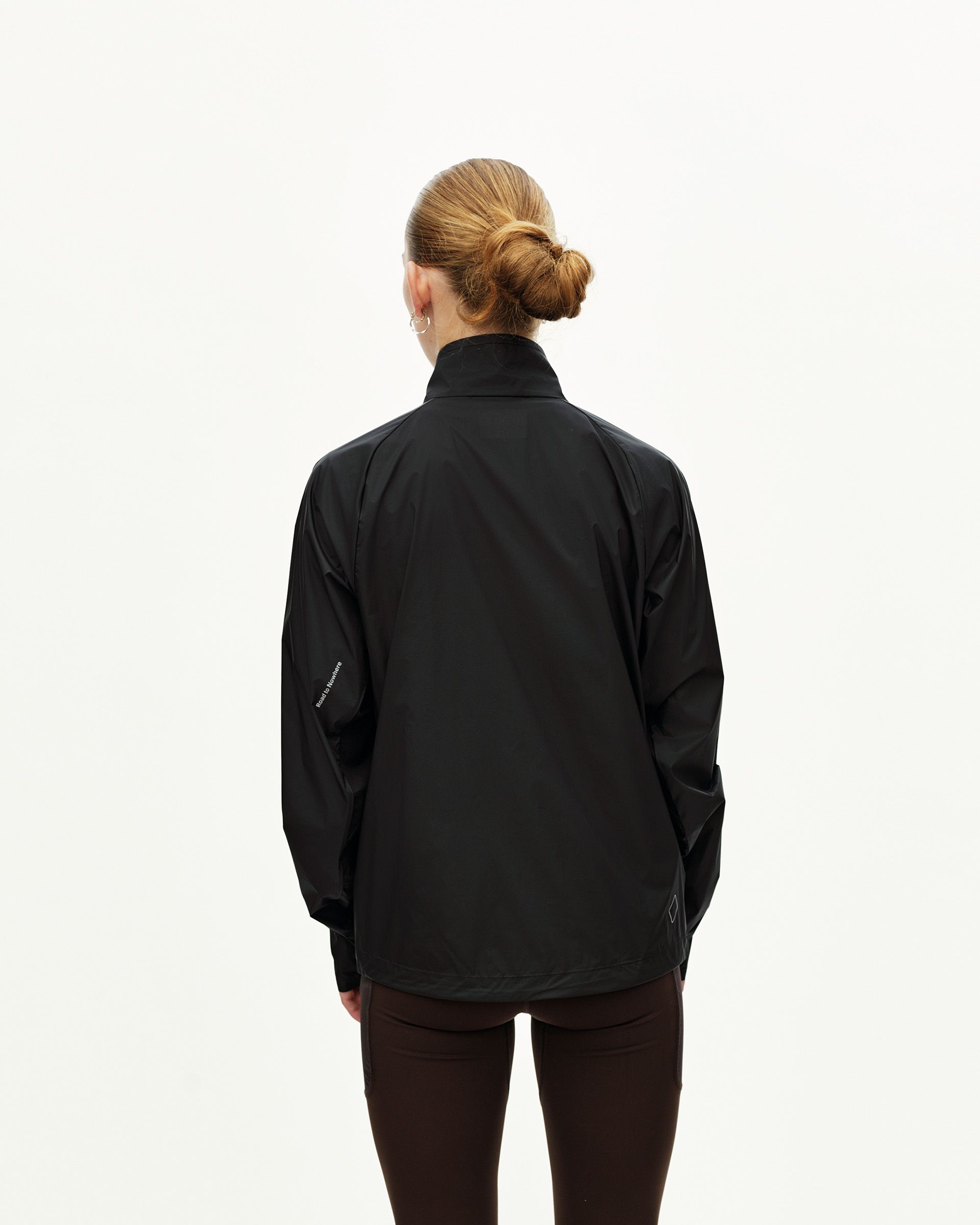 Black Balance Windproof cycling jacket on model, rear view with small reflective detail at hem