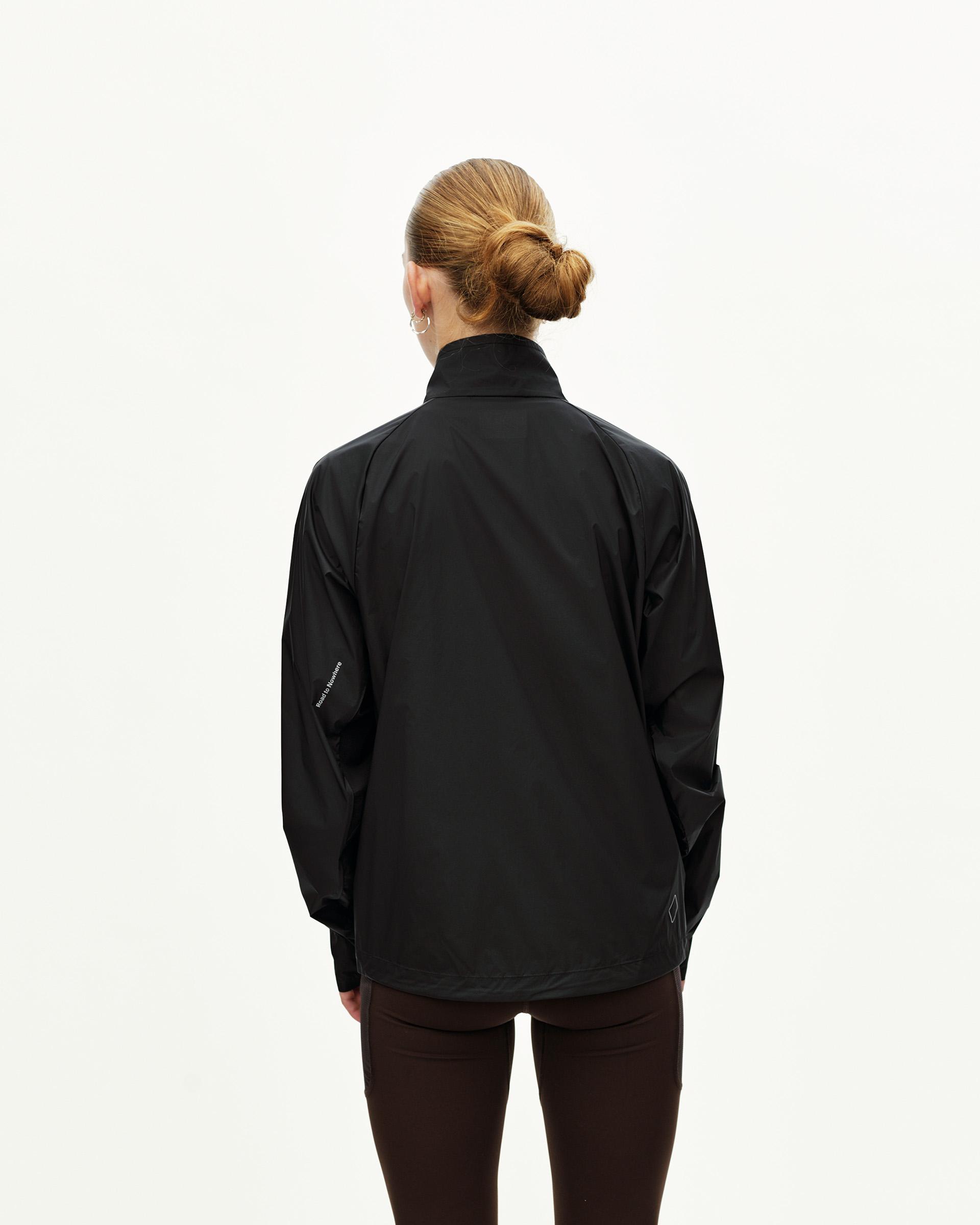 Black Balance Windproof cycling jacket on model, rear view with small reflective detail at hem